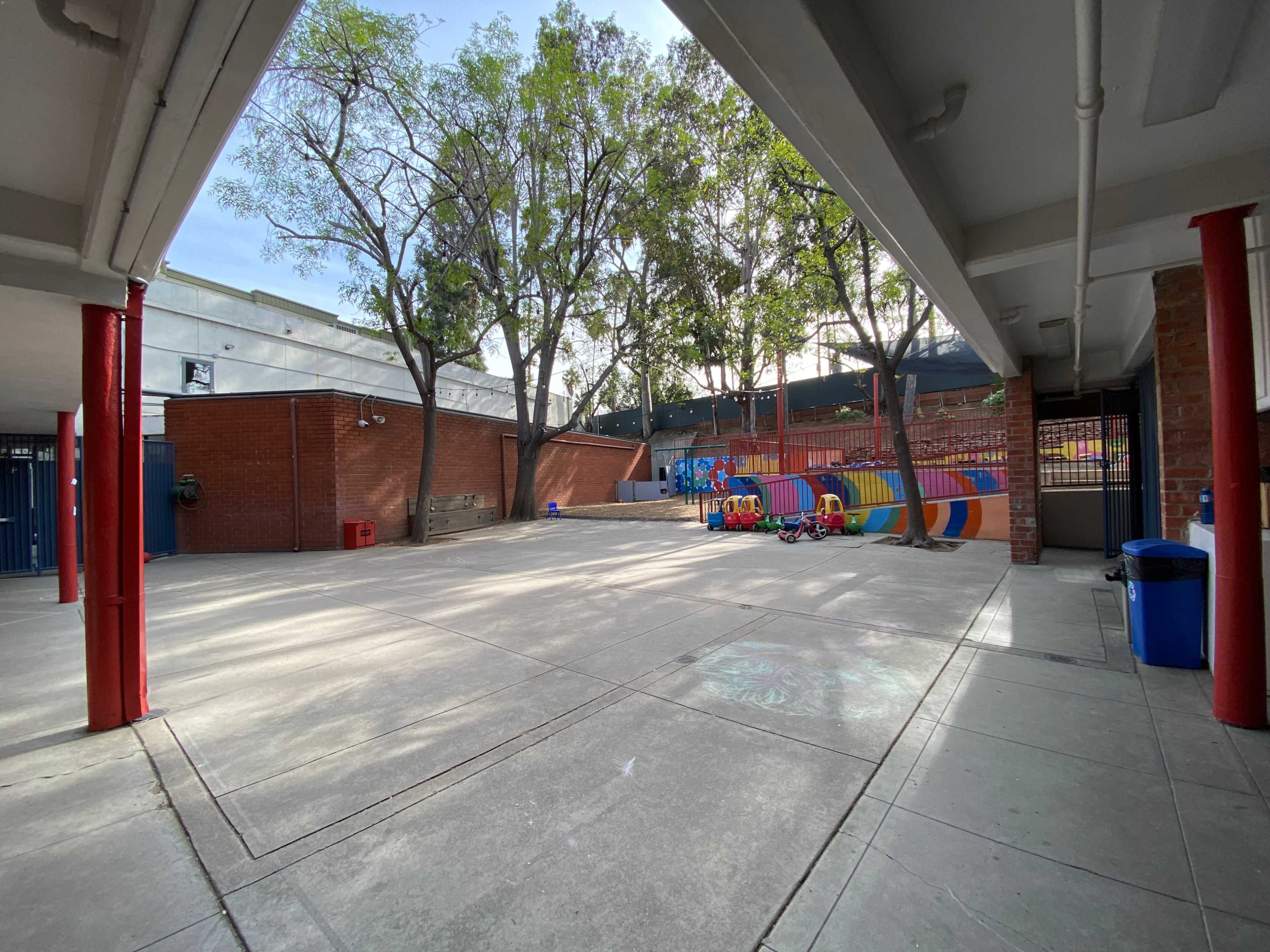 A playground area features colorful structures and trees, surrounded by brick and concrete walls.