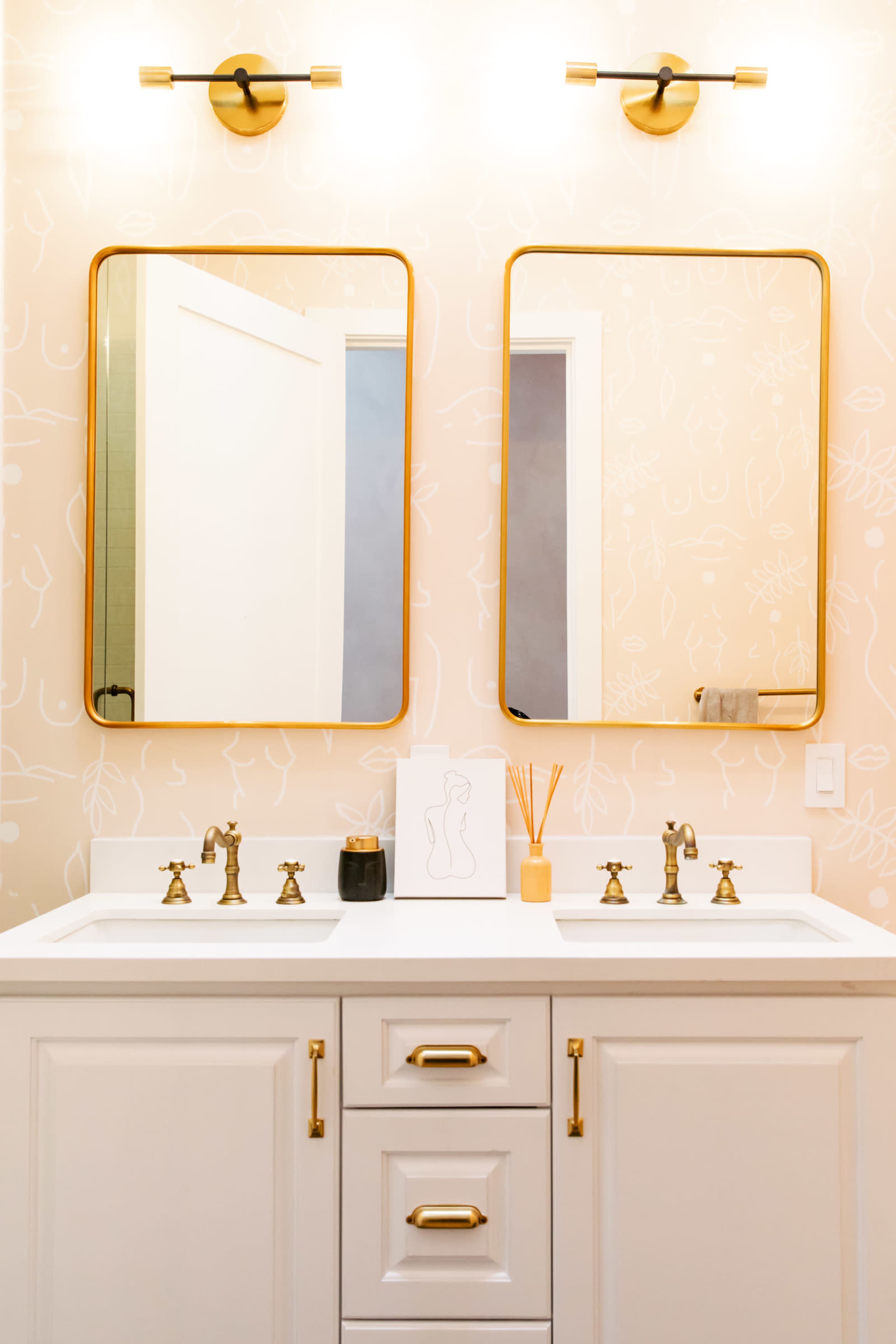 The image shows a modern bathroom vanity with two mirrors, a double sink, and decorative accents on the walls.