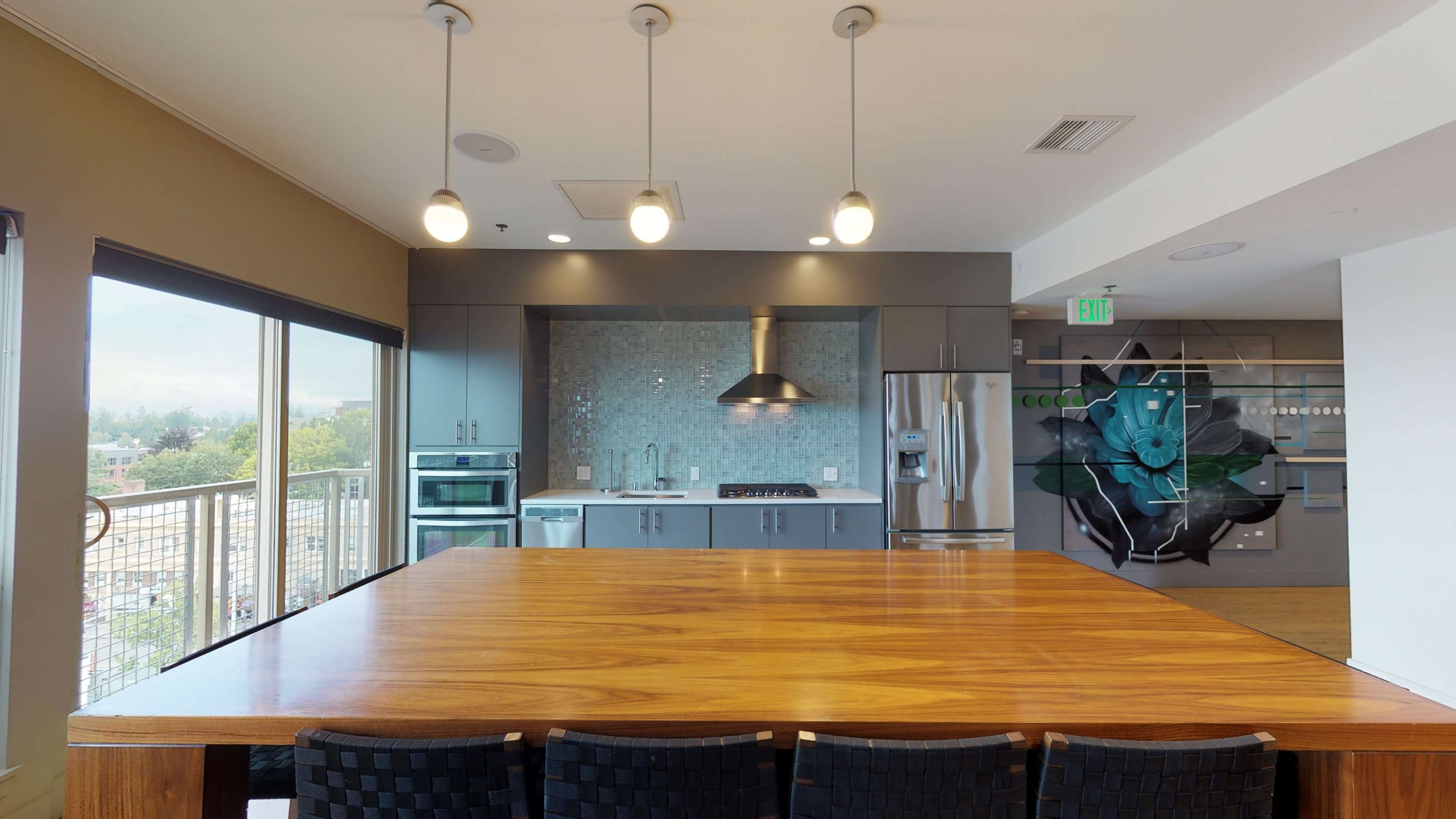 A modern kitchen features a large wooden table and sleek gray cabinets with stainless steel appliances.