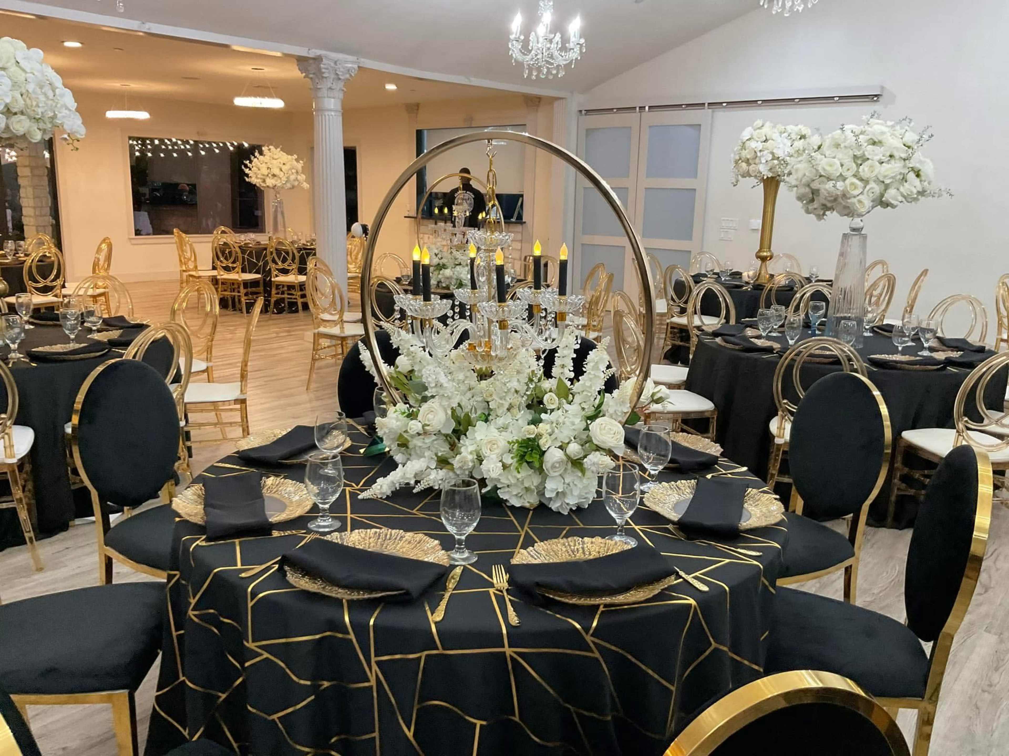 The image shows a beautifully arranged banquet hall with black and gold tables, adorned with floral centerpieces and elegant table settings.