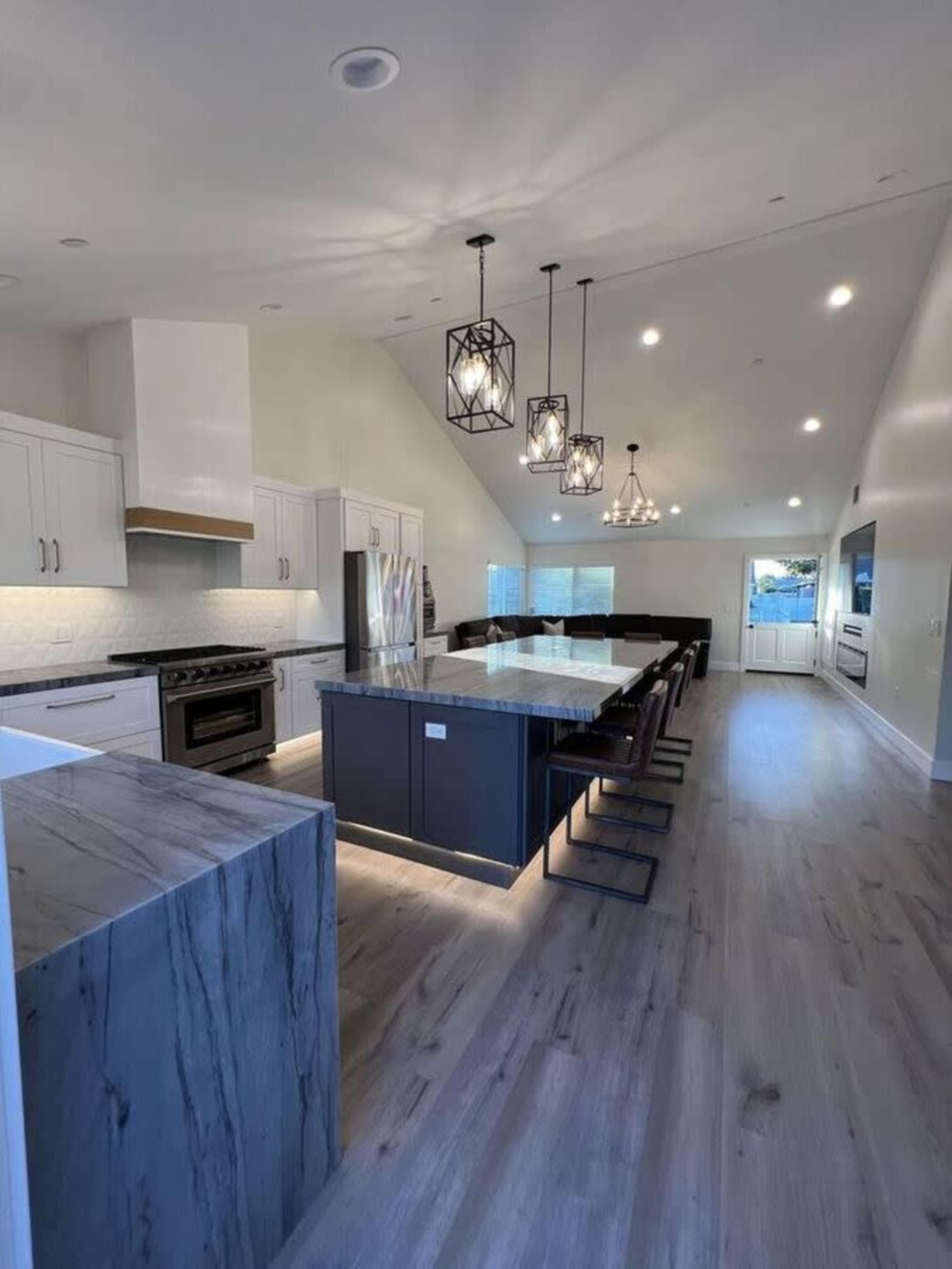A modern kitchen with a large island, sleek cabinetry, and pendant lighting over a dining area.