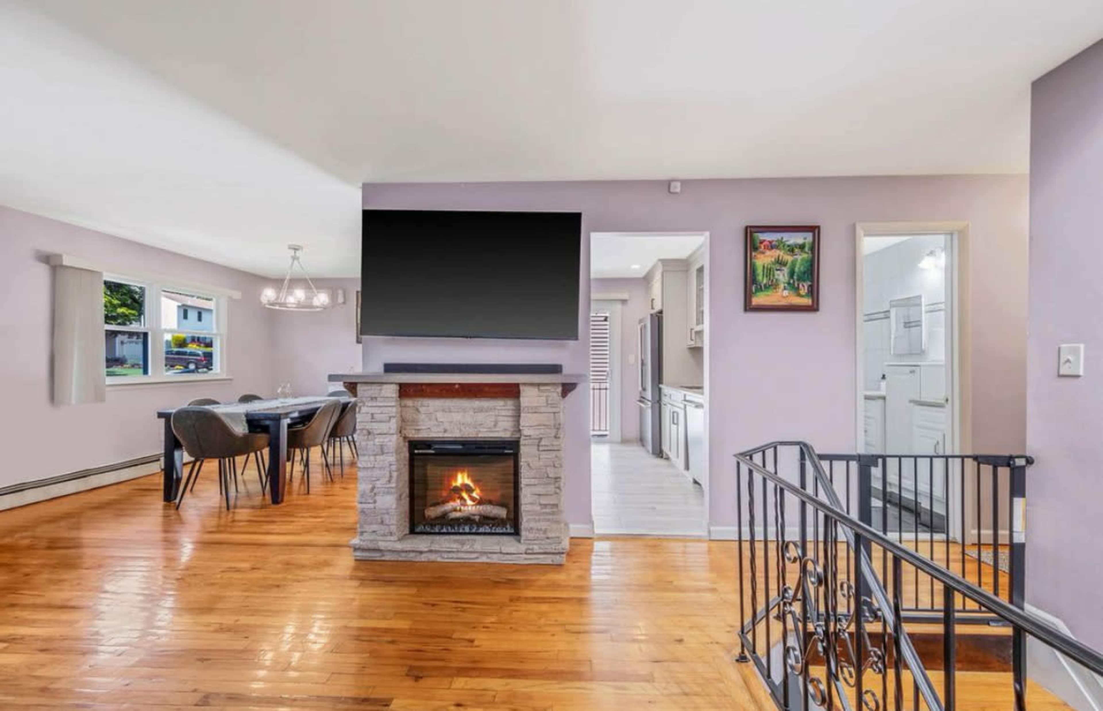 The image shows a modern living space with a stone fireplace, a television mounted above it, and a dining area visible in the background.