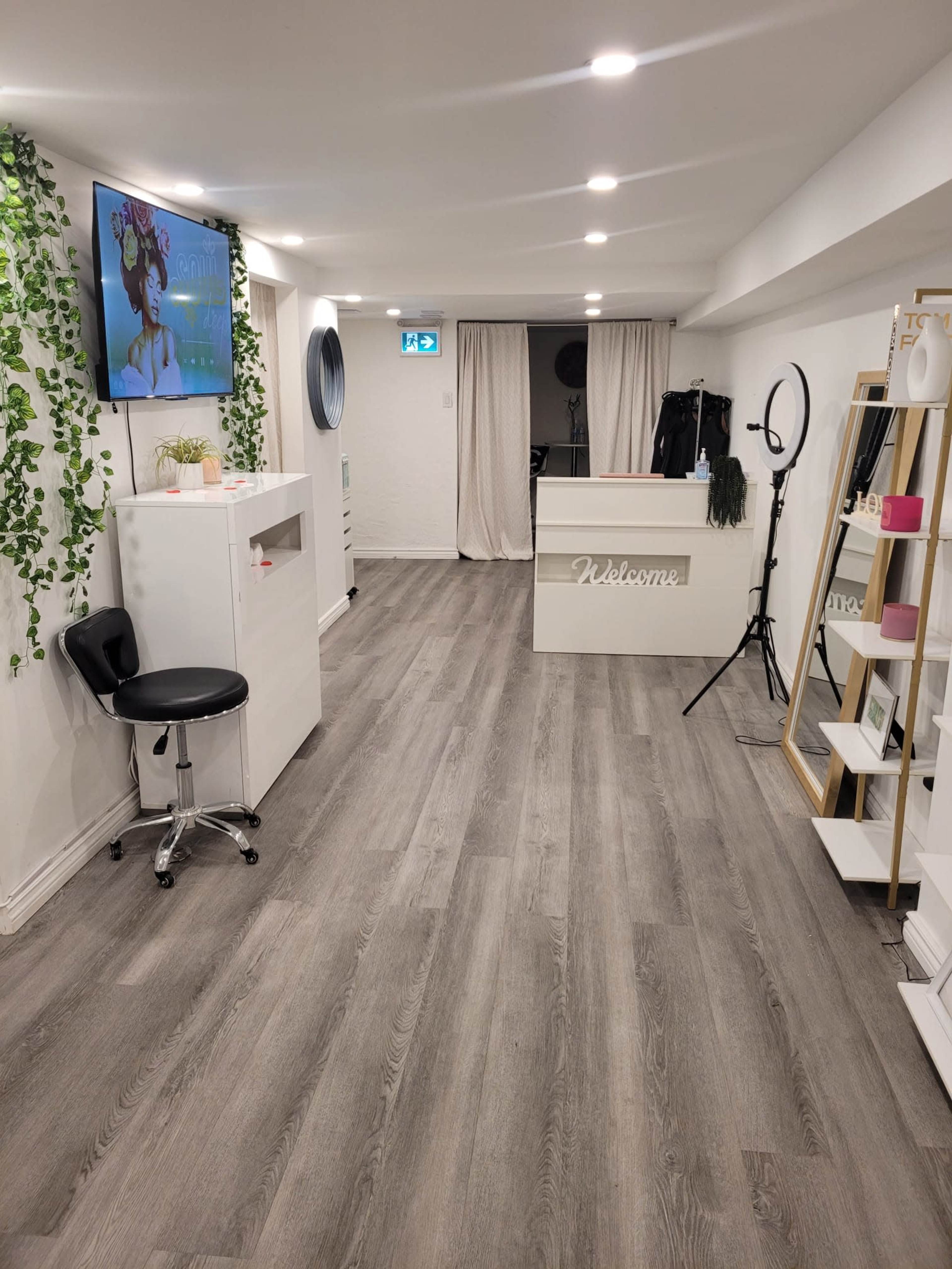 A well-lit interior space resembling a salon or beauty studio, featuring a reception desk, a large mirror, and various display shelves.