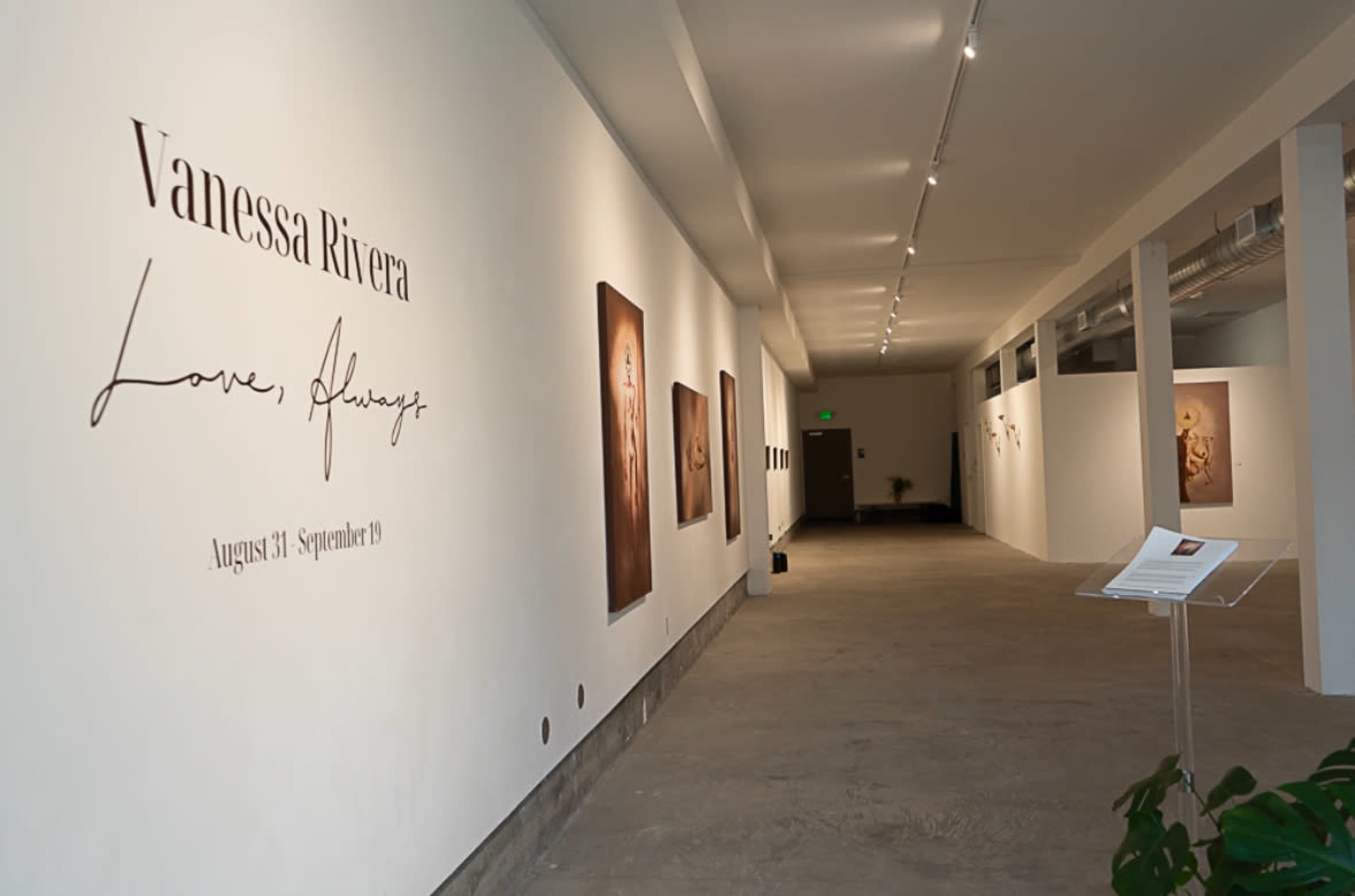 The image shows an art gallery interior with white walls featuring an exhibition titled "Love, Always" by Vanessa Rivera, running from August 31 to September 19, with framed artworks displayed along the walls.