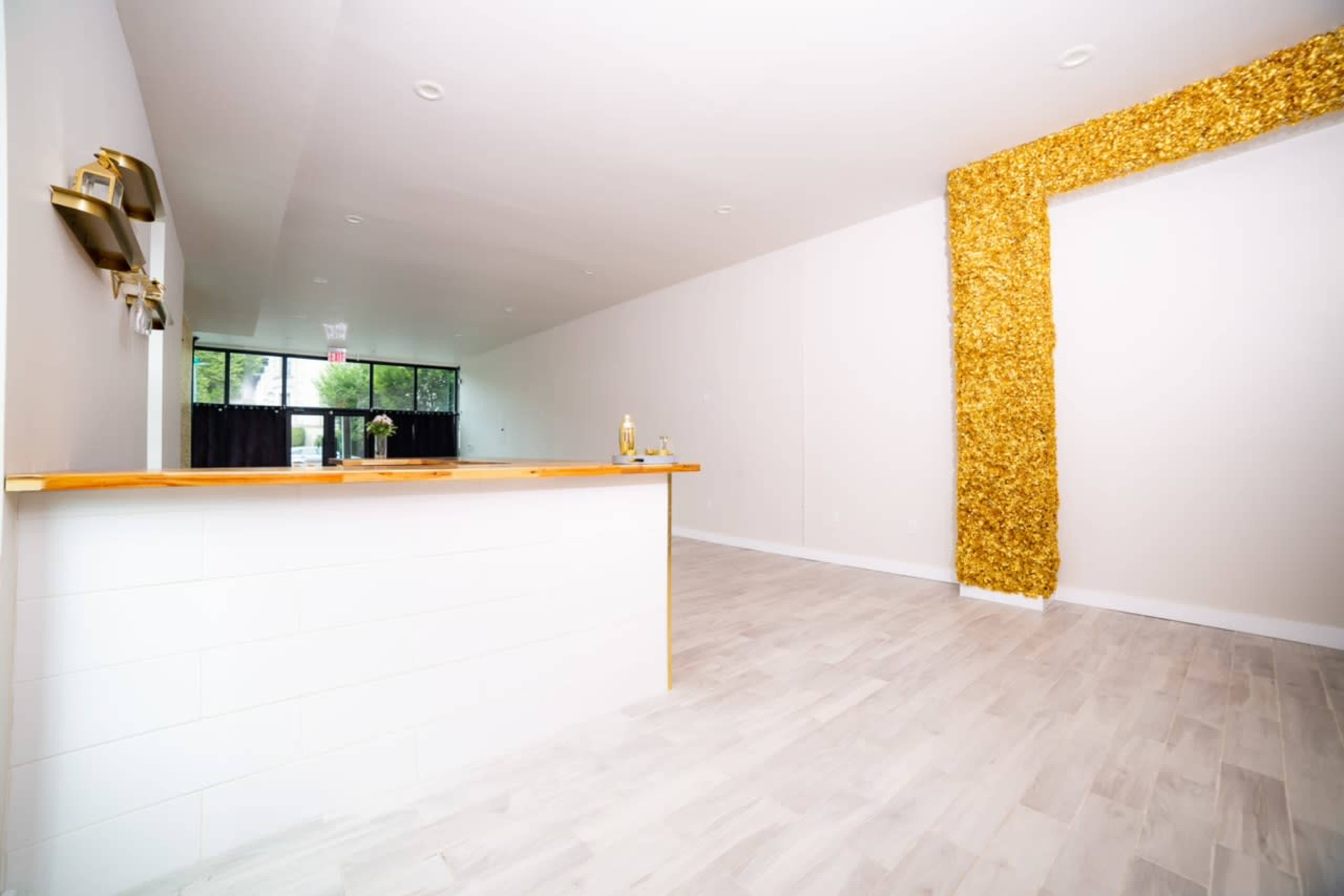 A spacious interior with a wooden countertop on the left and a gold-accented wall on the right.