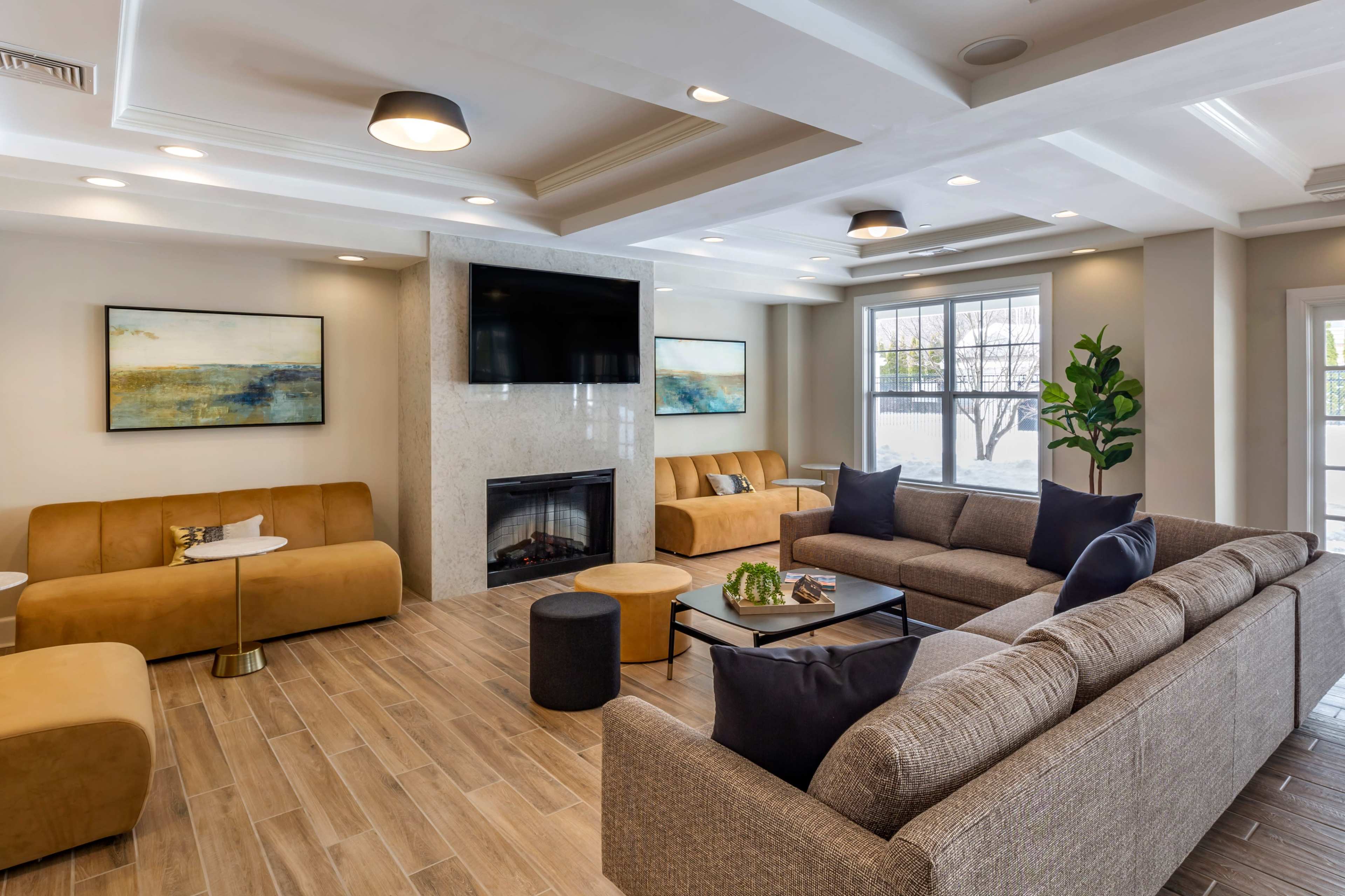 A spacious lounge area features modern furniture, a fireplace, and large windows allowing natural light.