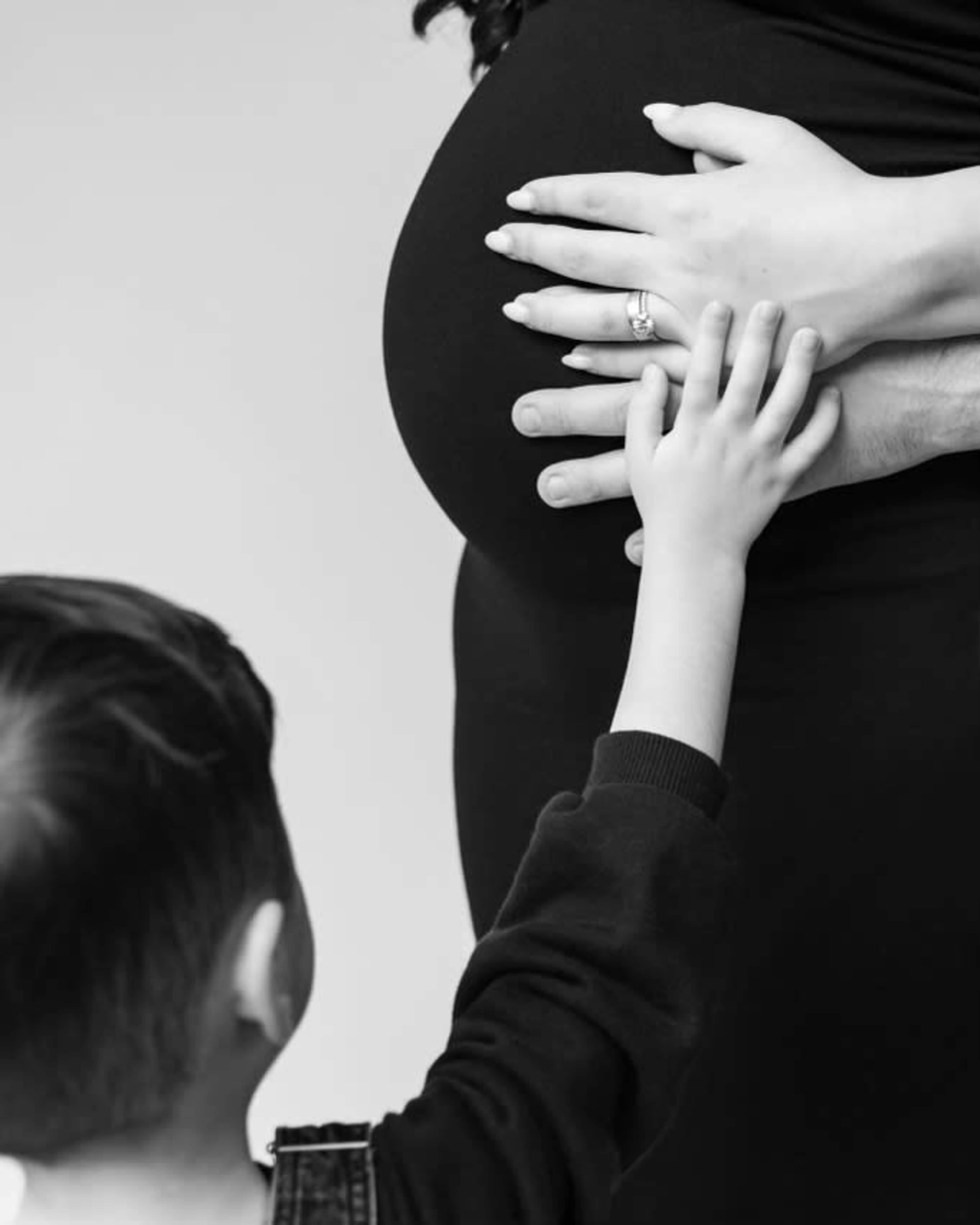 A small child reaches out to touch the belly of a pregnant woman.