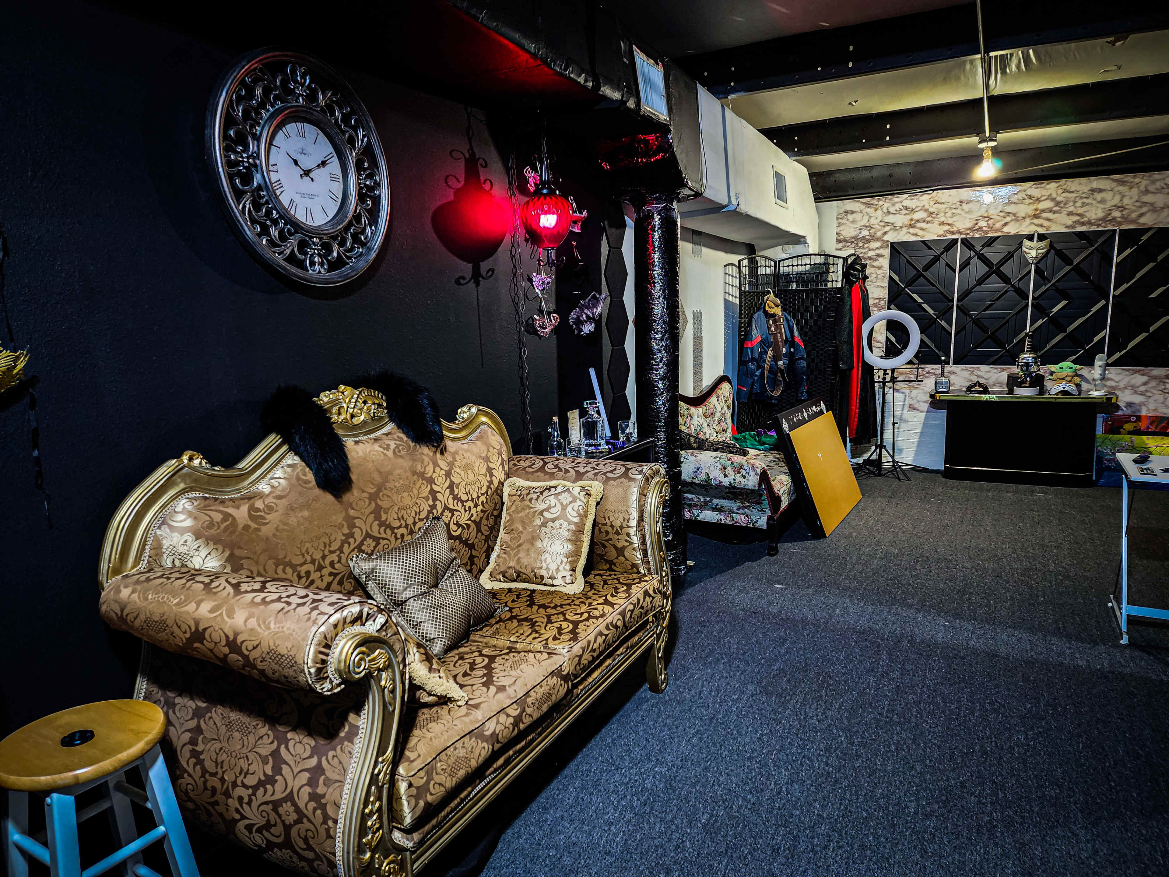 A stylish room with ornate furniture, a large wall clock, and various decorative items, including a mirror and clothing rack.