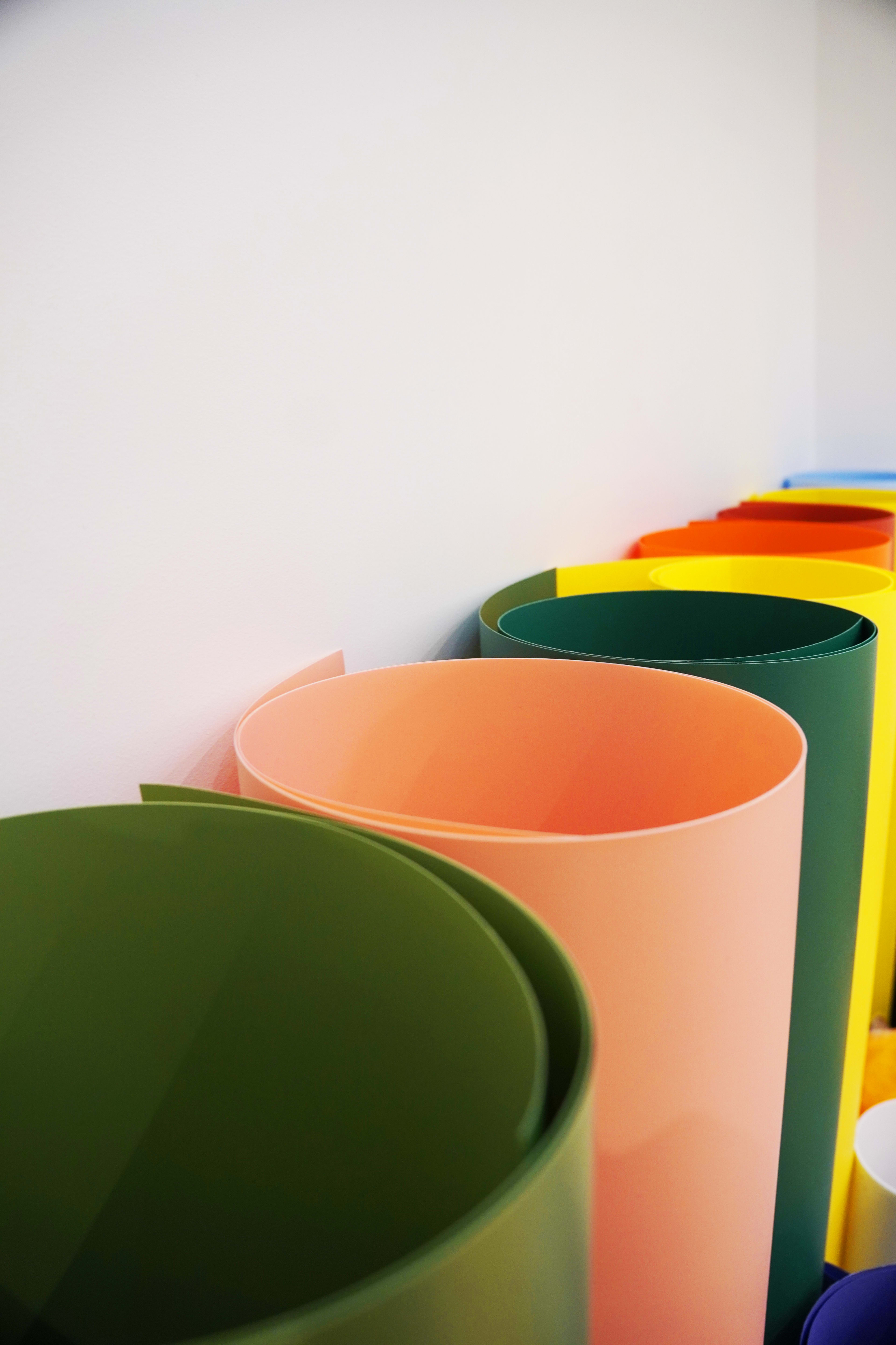 A collection of rolled sheets in various colors arranged in a line against a white wall.