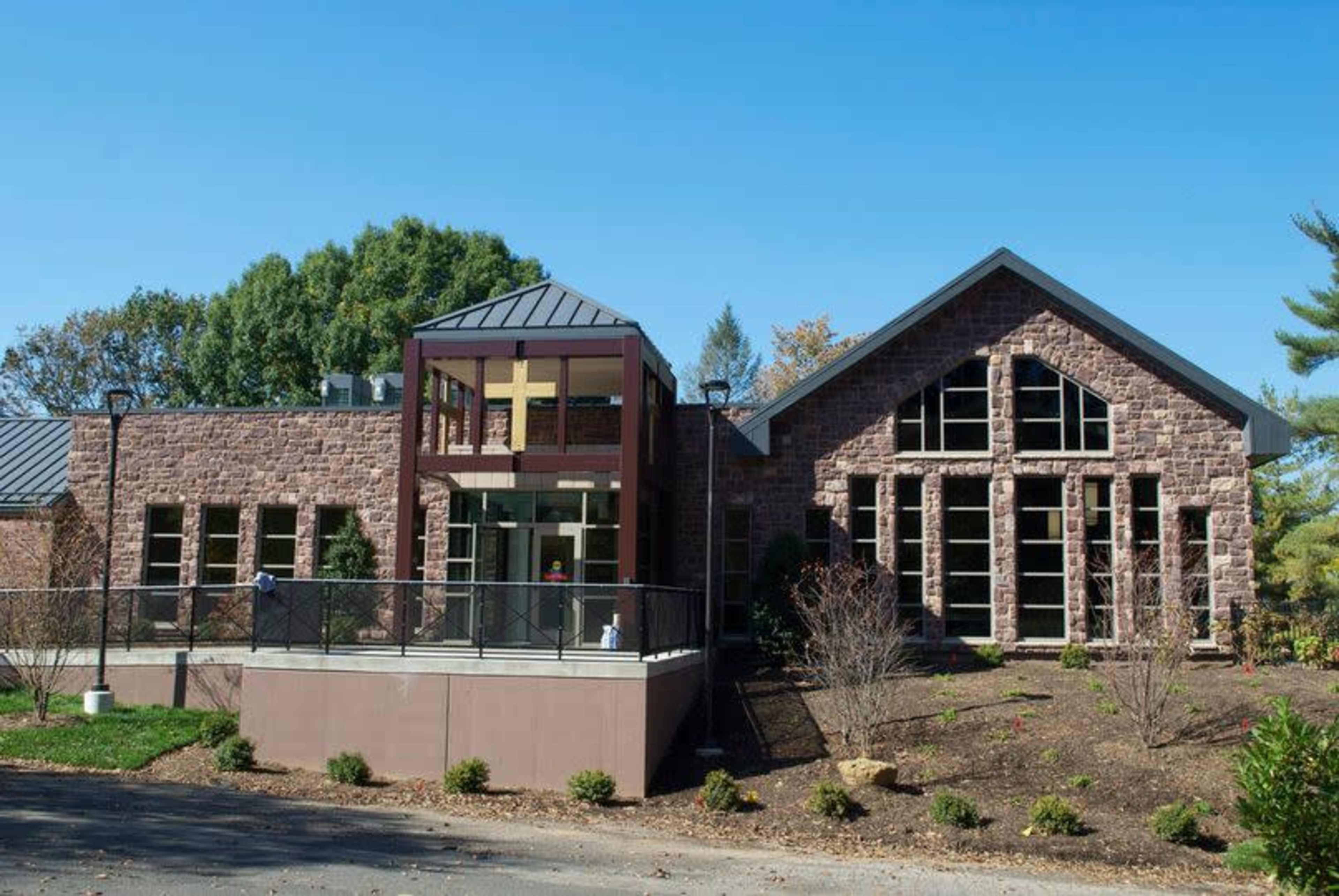 A modern stone building with large windows and a distinctive entrance featuring a glass and metal structure.