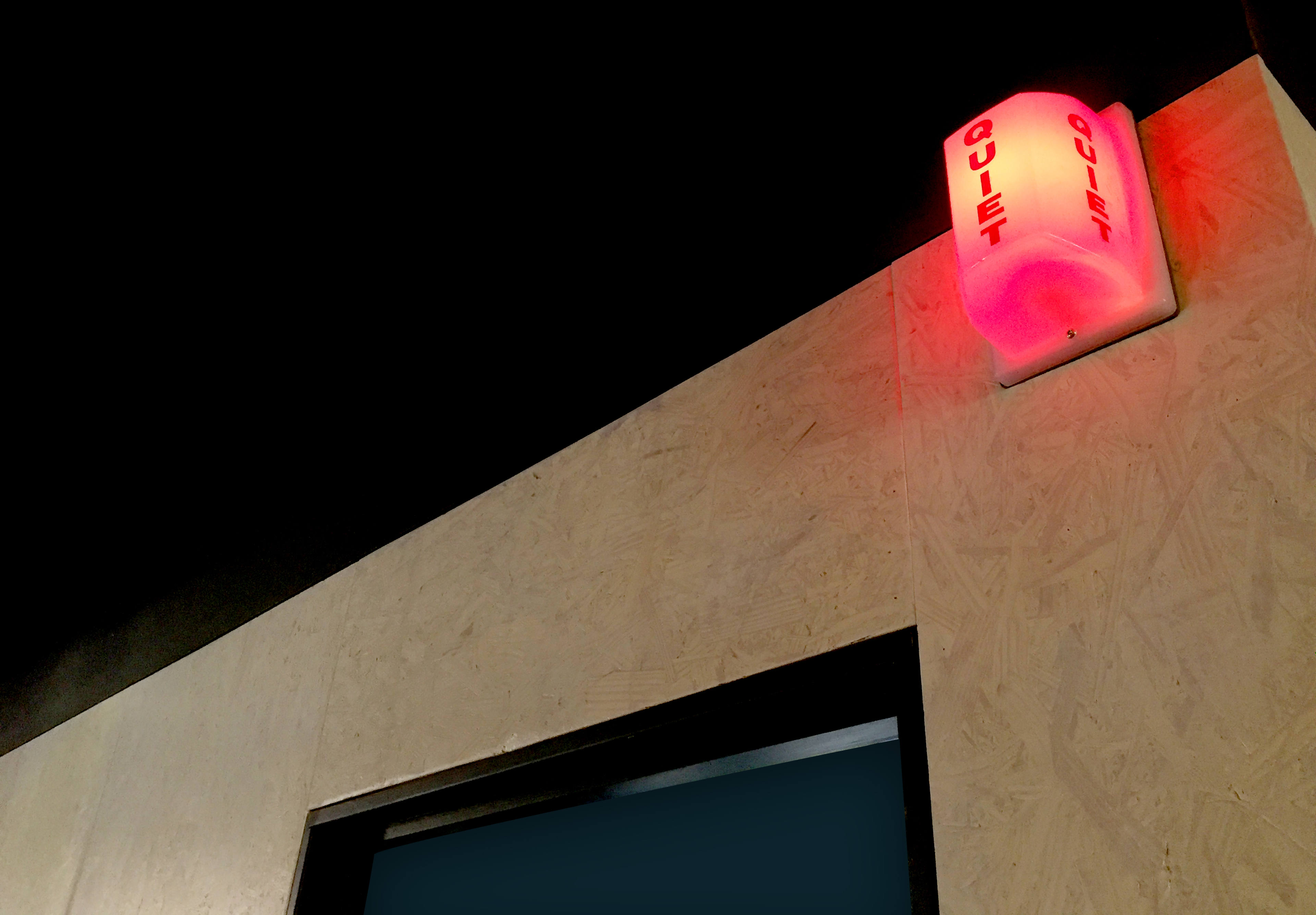 A red light with the word "QUIET" illuminated is mounted on a wall above a doorway.