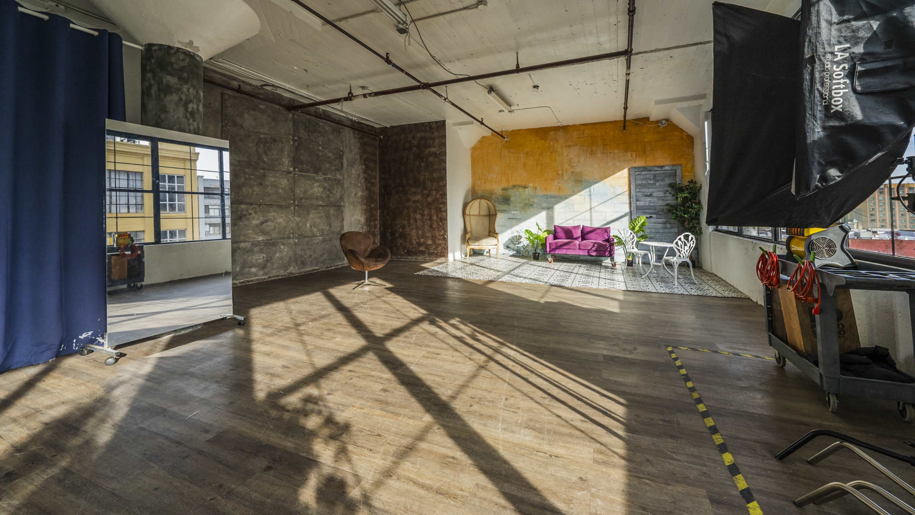 A spacious loft-style interior with exposed walls, wooden flooring, and various seating areas including a chair and a purple couch.