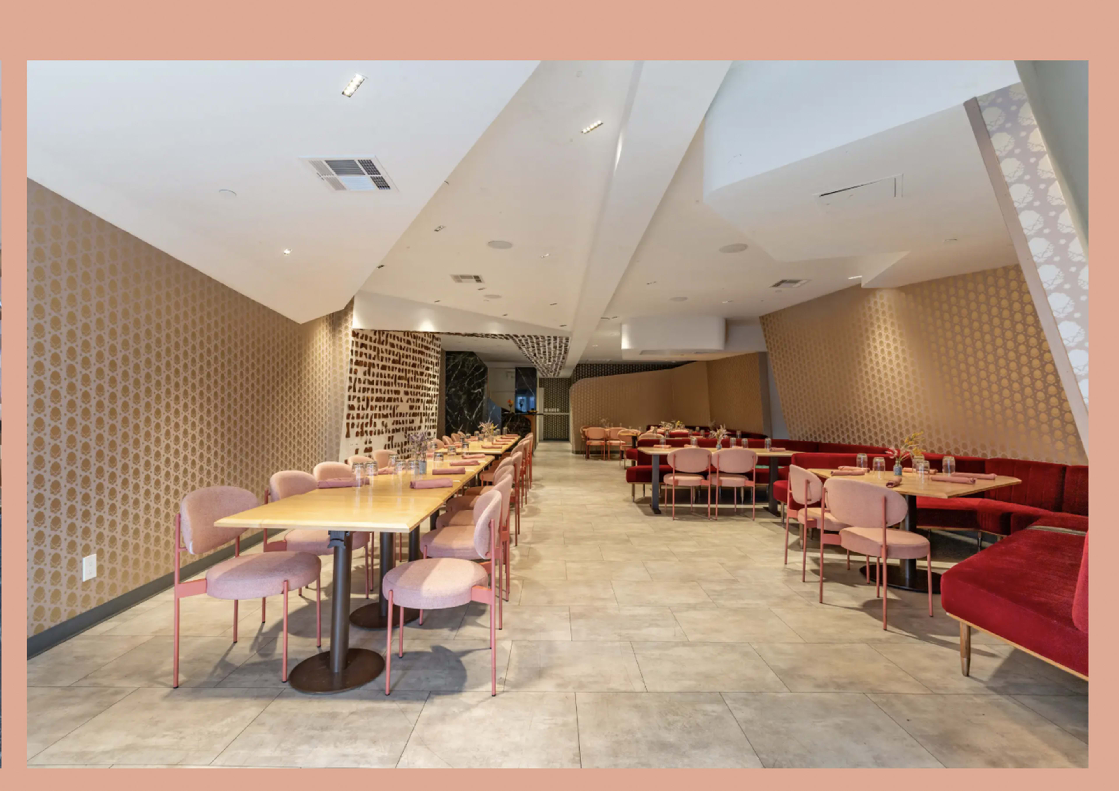 The image shows a modern restaurant interior with multiple seating areas featuring pink chairs and wooden tables against patterned walls.