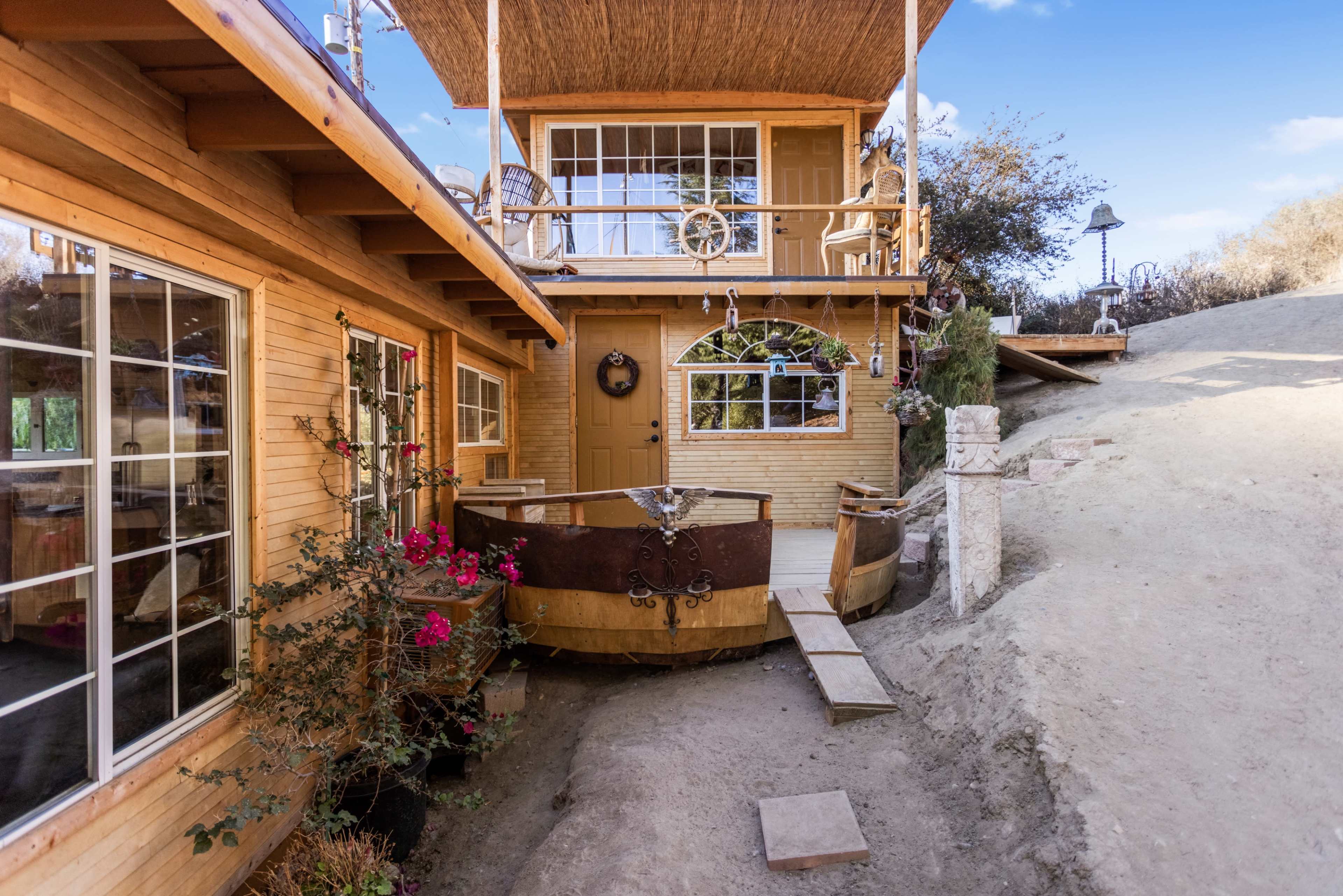 A wooden structure with two stories, featuring a small wooden boat as a decorative element and a pathway leading to the entrance.
