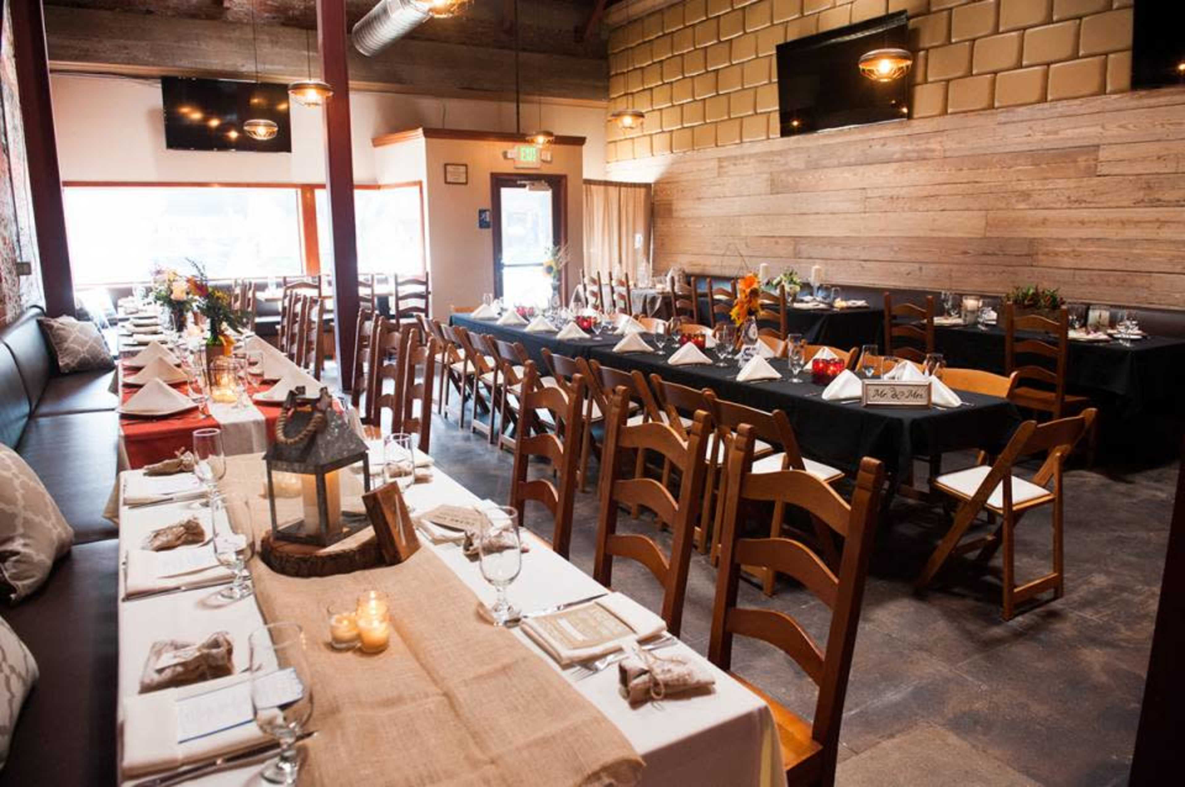 A spacious dining area with long tables set with utensils and decorations, featuring a mix of black and white tablecloths arranged for a special event.