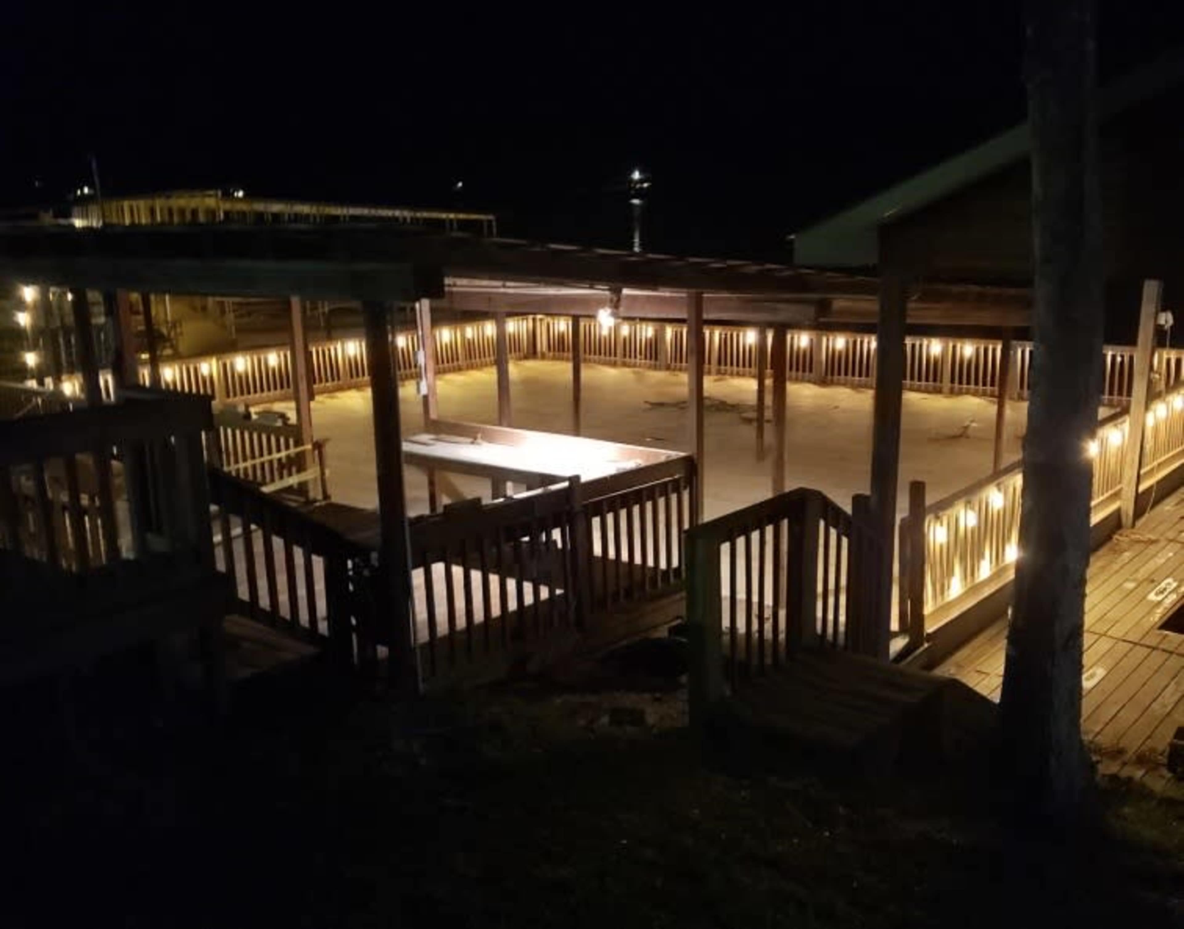 A wooden deck area with lights illuminating the surrounding structure at night.