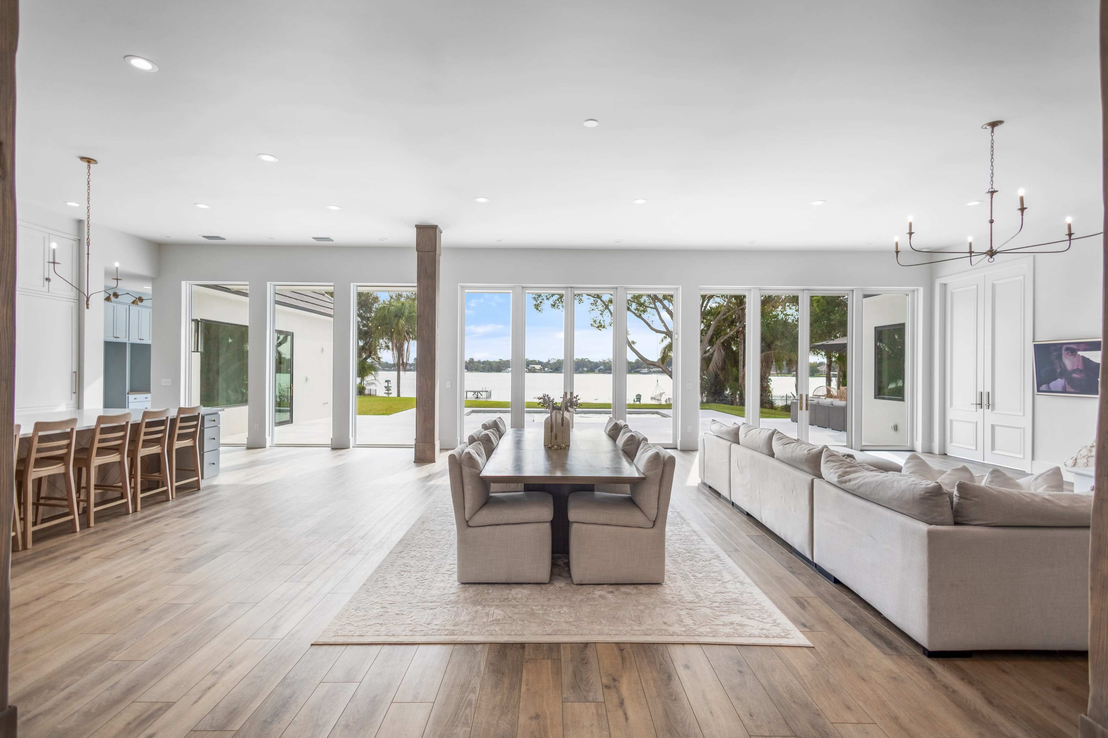 A spacious, elegantly designed living area that opens to a view of the outdoors, featuring a dining table, comfortable seating, and large windows.