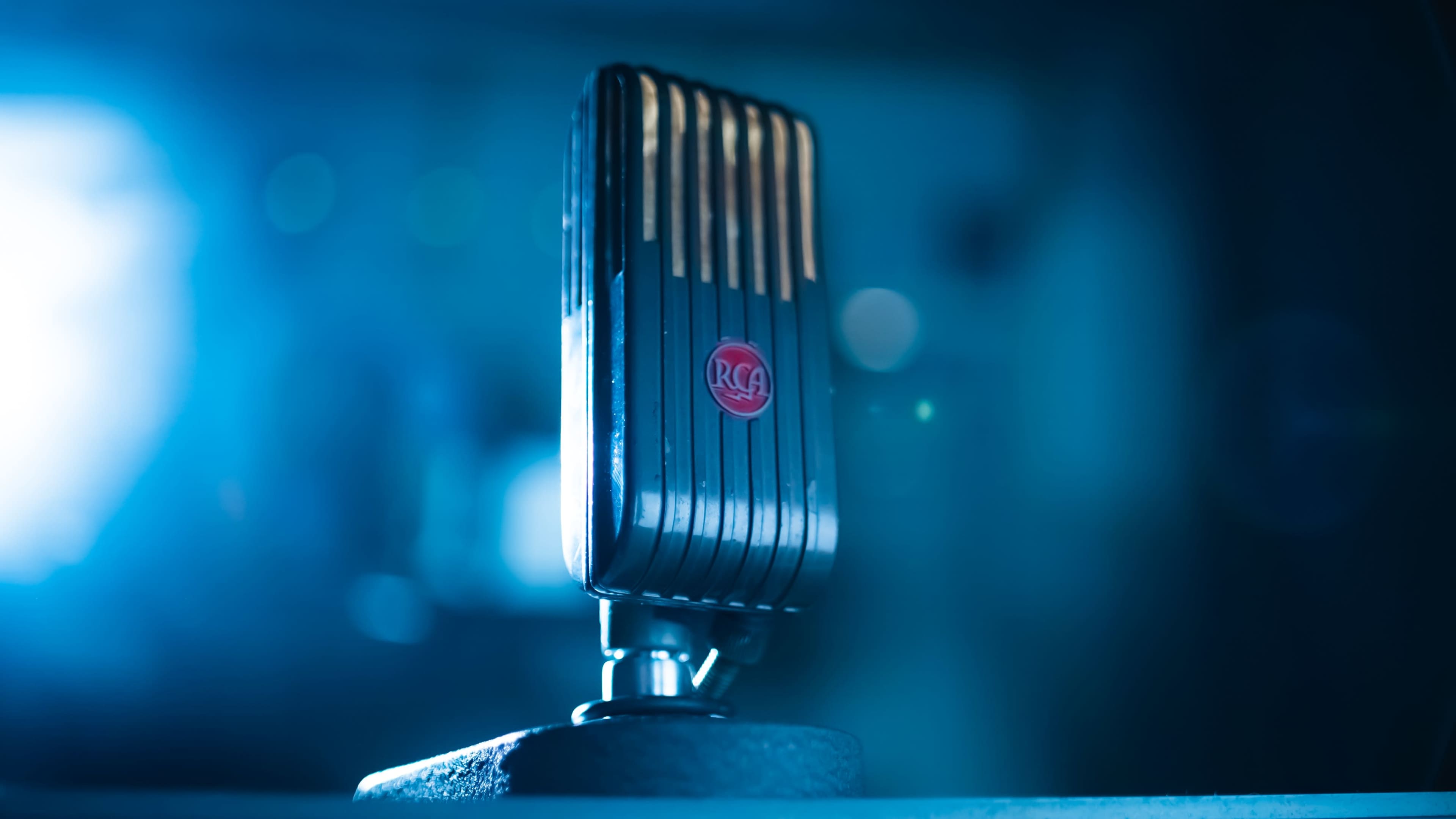 A vintage RCA microphone stands prominently on a surface with a soft blue background.