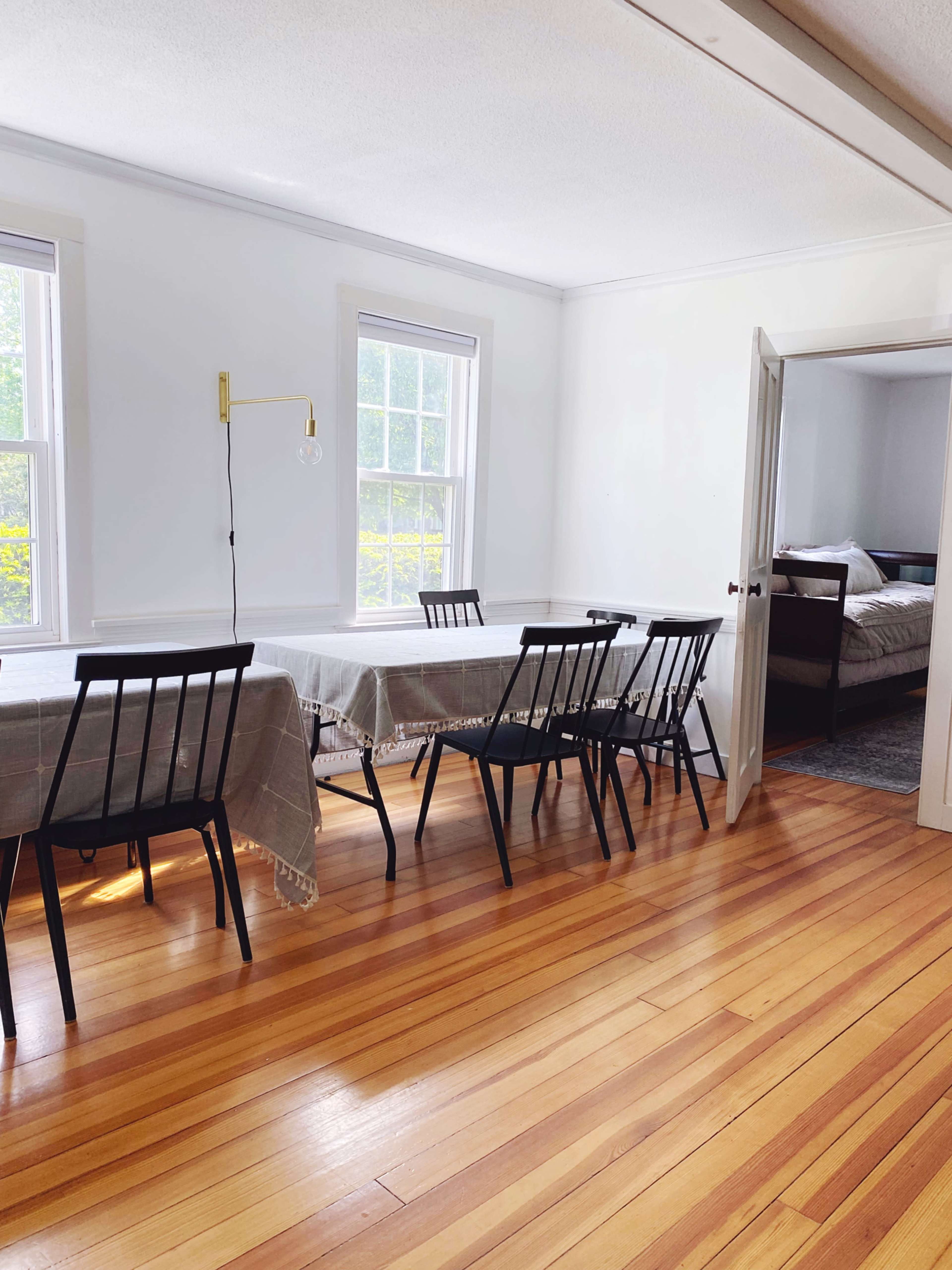 A dining area with several black chairs and tables set against a backdrop of light-colored walls and wooden floors.