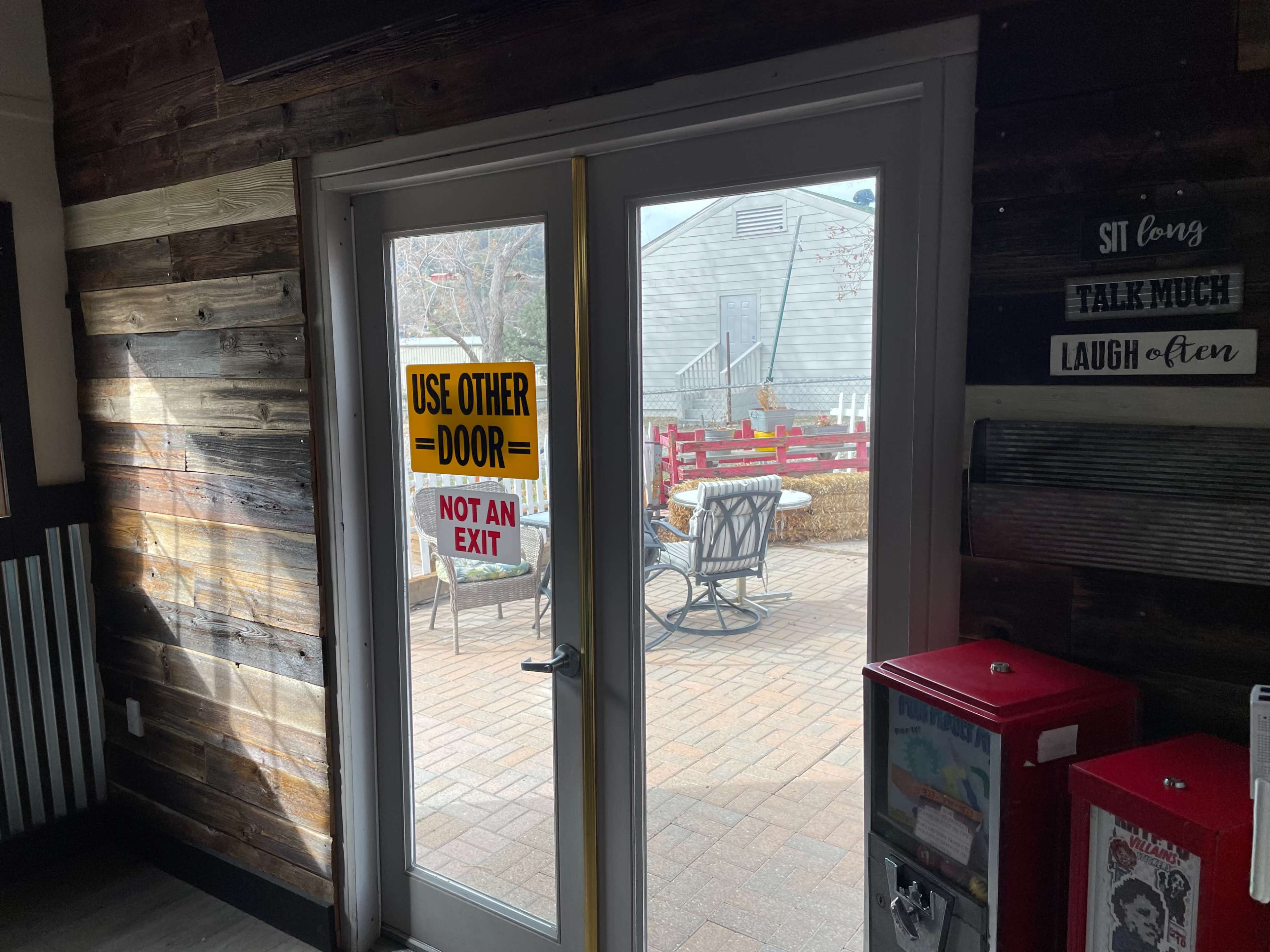 A double door leads to an outdoor seating area marked with a sign that instructs to use the other door.