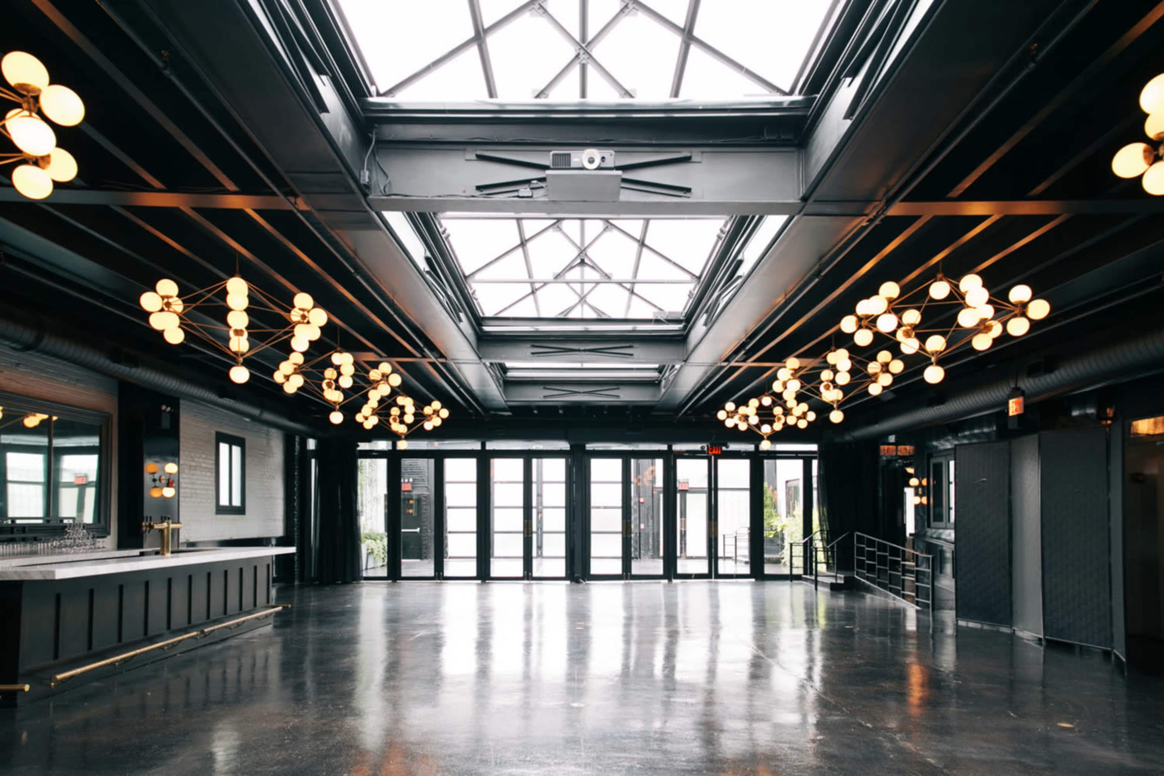 A spacious interior with large windows, black metal beams, and modern lighting fixtures.