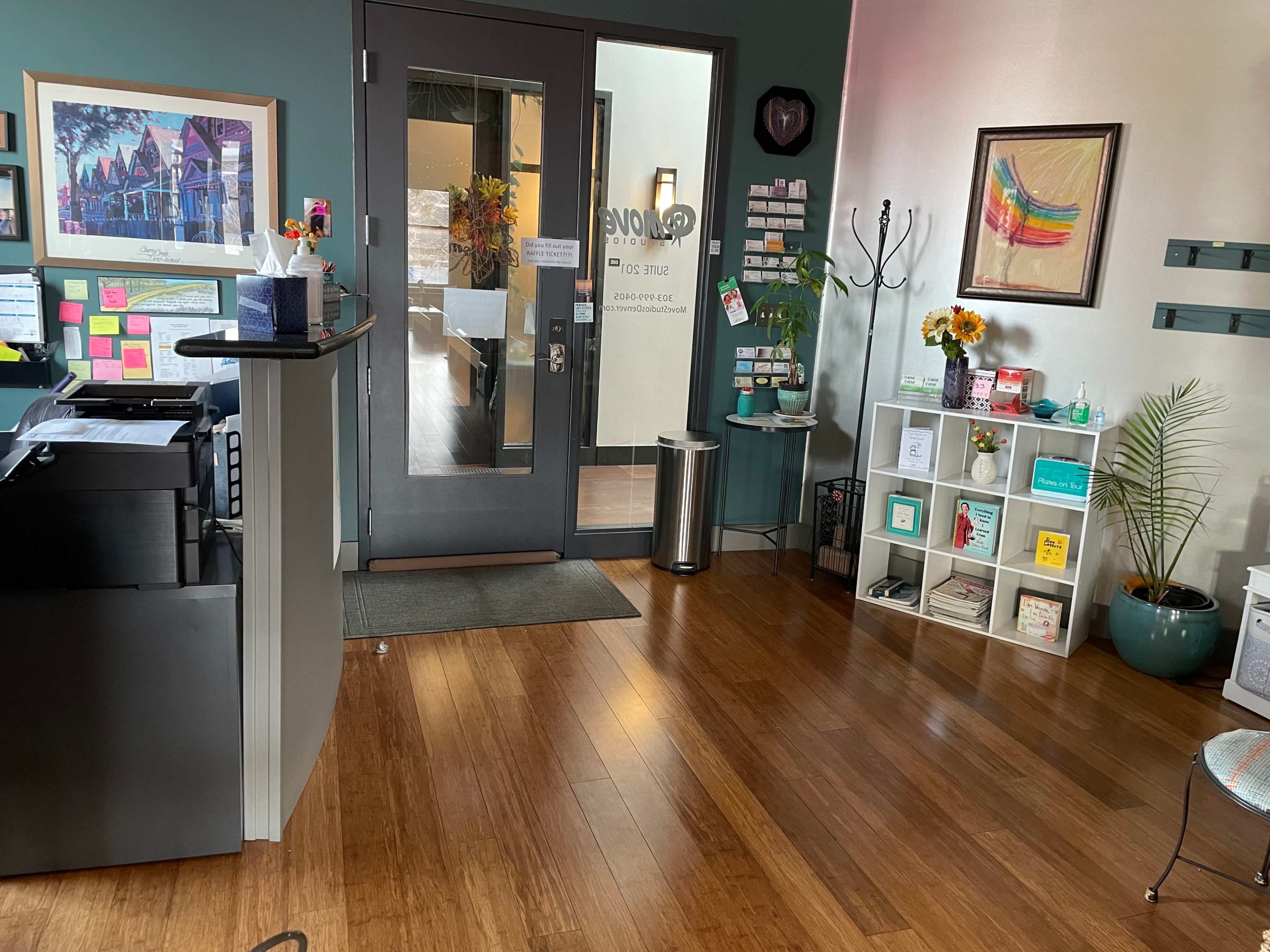 A reception area with a front desk, seating, and a display of colorful art and wellness materials against a wall.