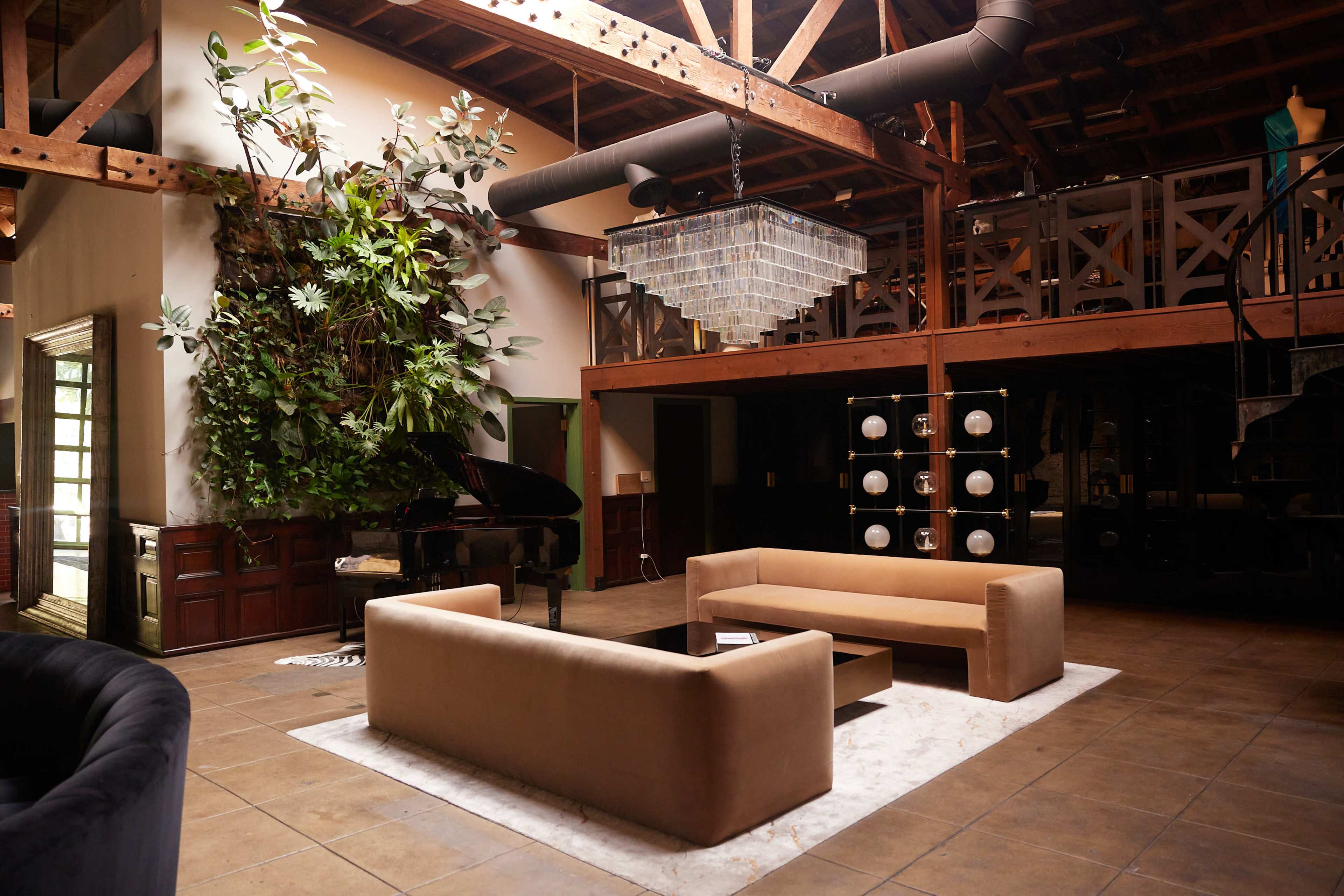 The image shows a spacious interior with a grand piano, modern sofas, a chandelier, and a large indoor plant.