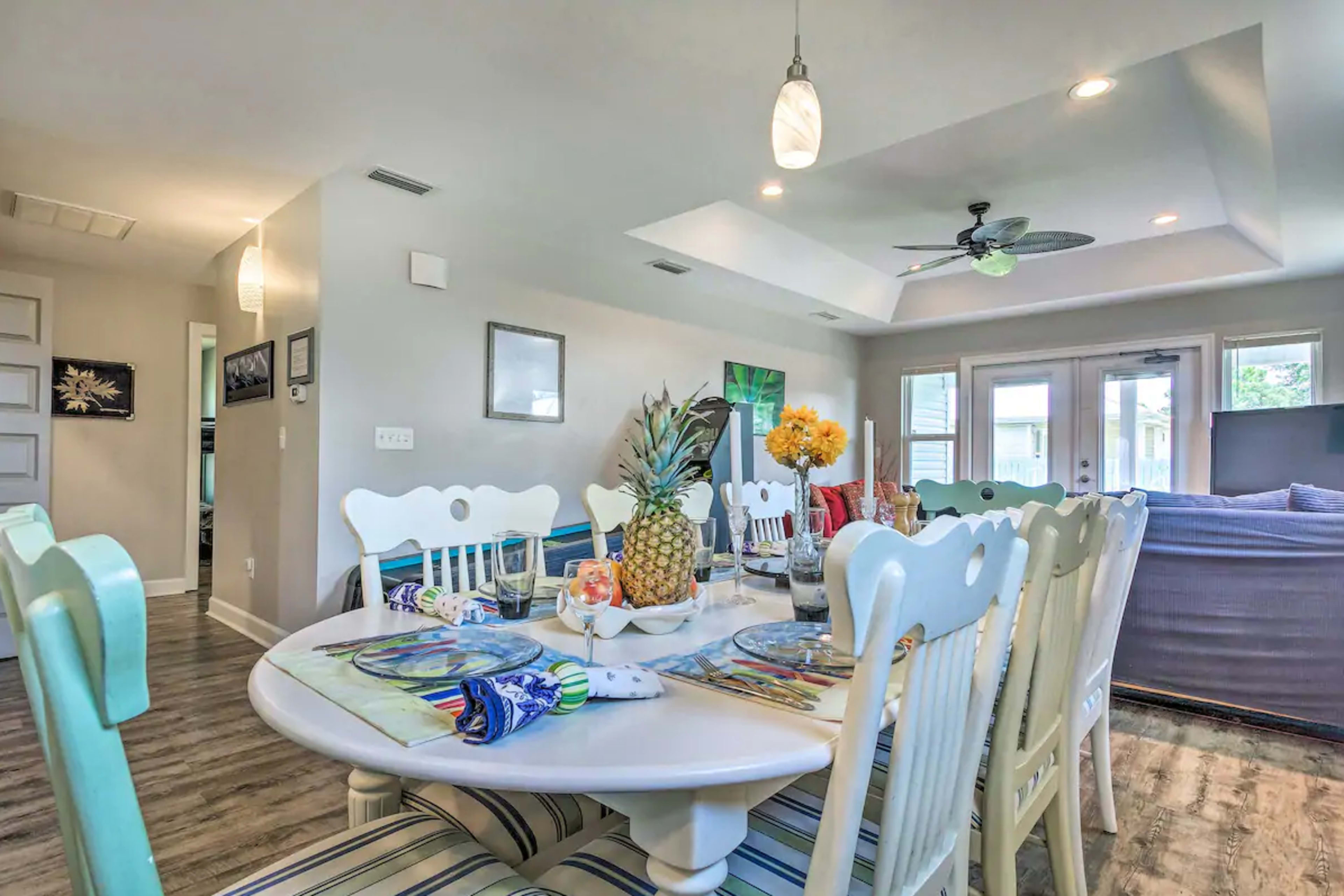 A spacious dining area features a white wooden table set with colorful plates and decorations, surrounded by matching chairs.