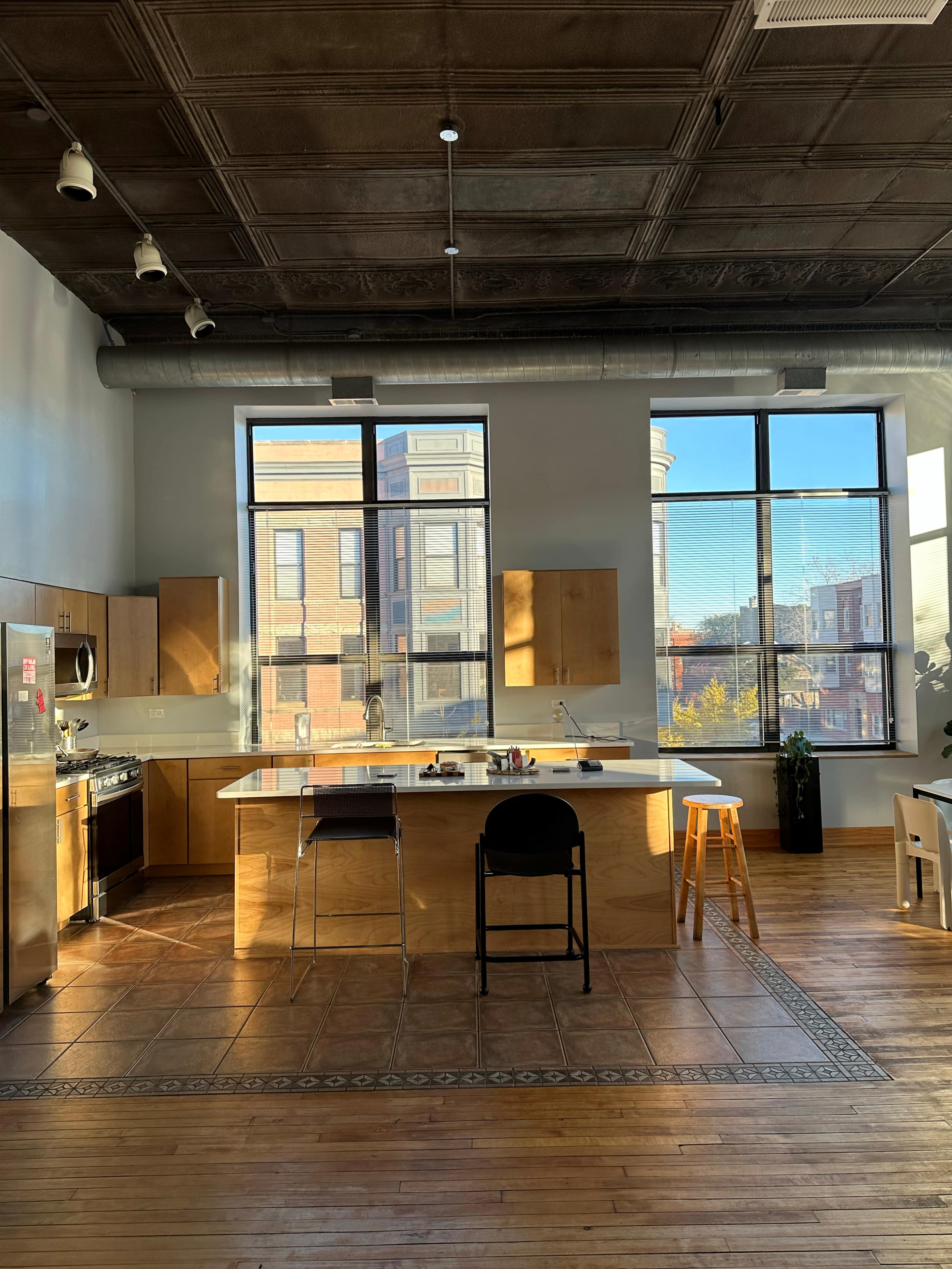 A spacious kitchen features a central island, wooden cabinetry, and large windows allowing natural light to fill the room.
