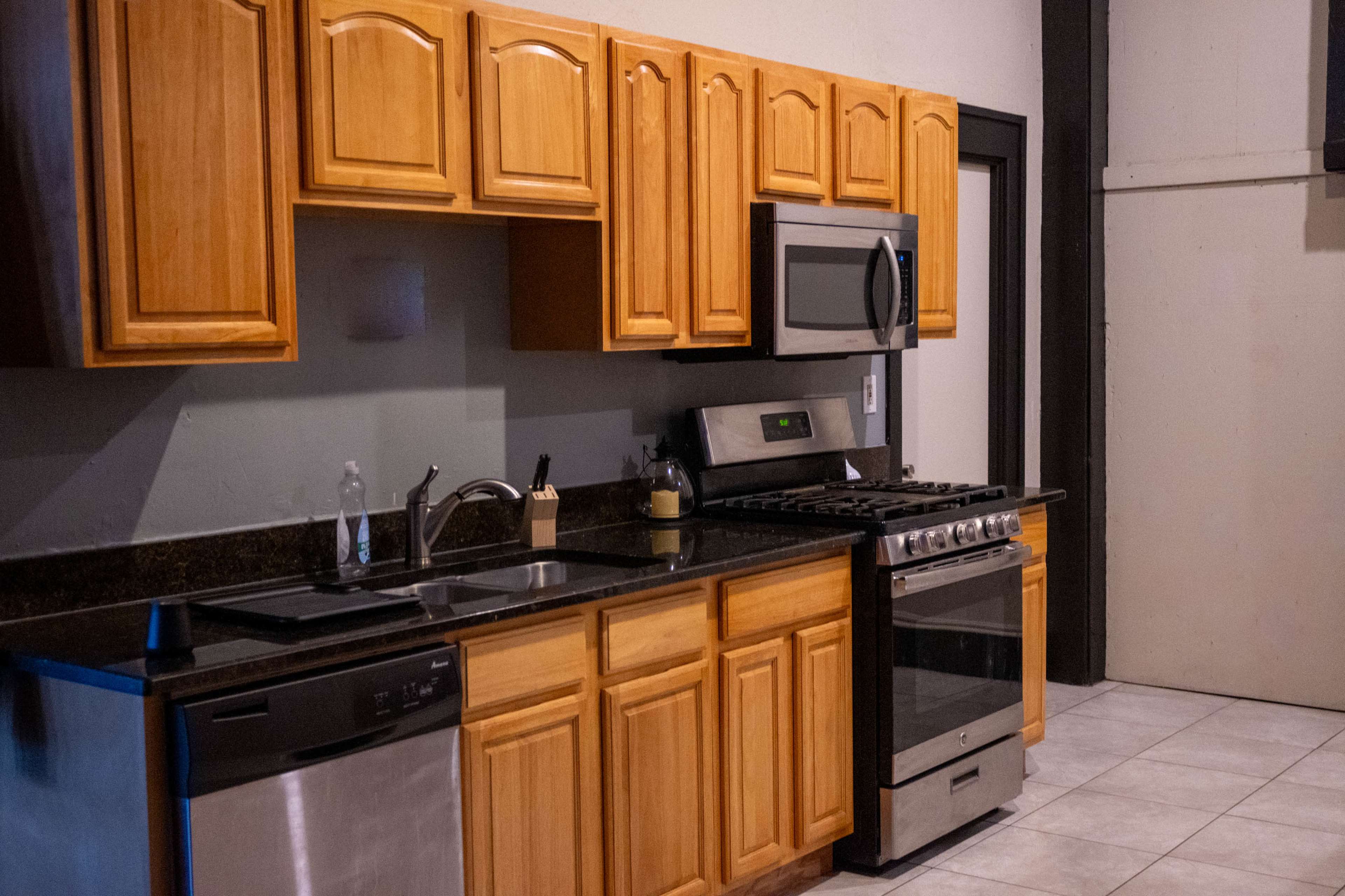 A kitchen with wooden cabinetry, stainless steel appliances, and a granite countertop.