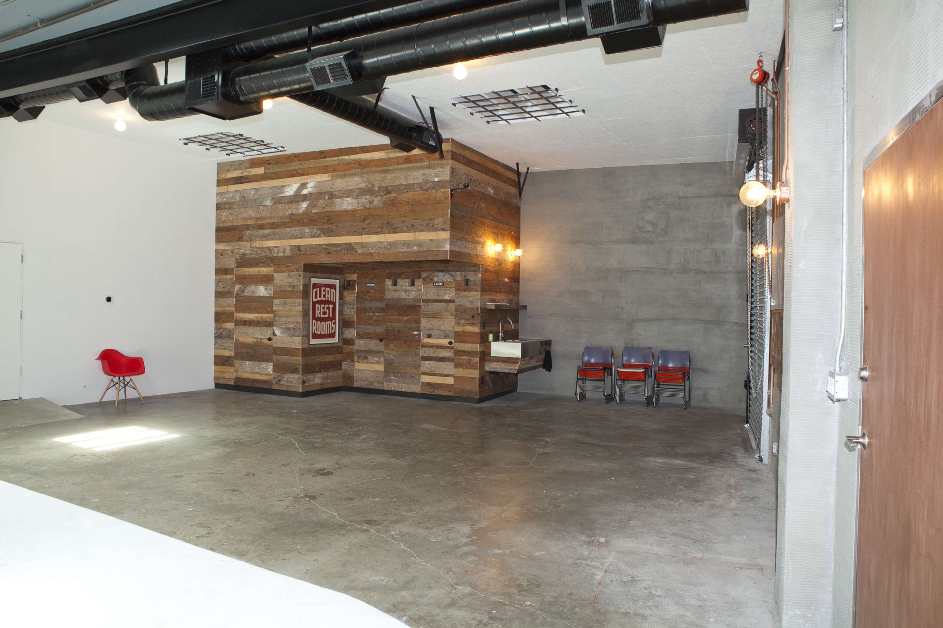 An interior space featuring a wooden accent wall, concrete walls, and a few stacked chairs in the corner.