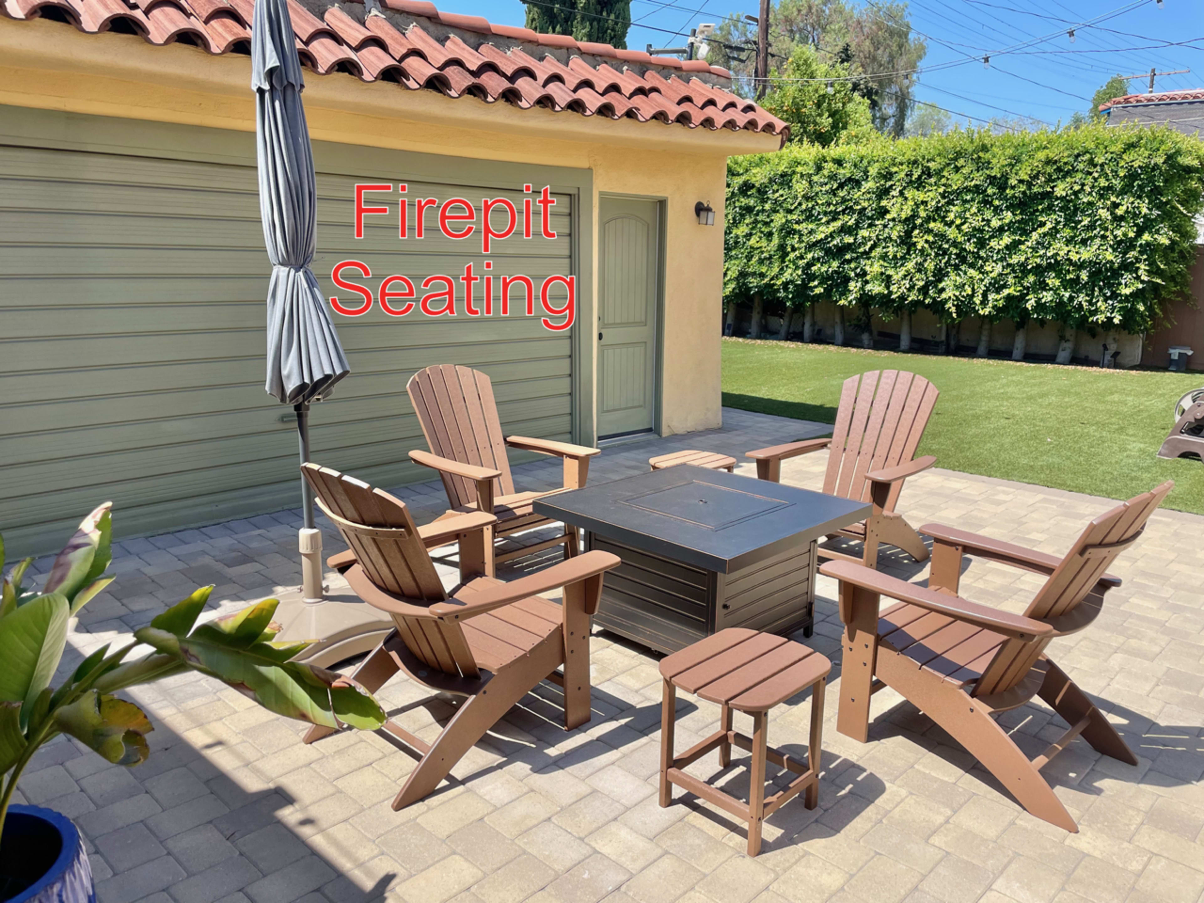 A patio area features a firepit surrounded by wooden chairs and a small table, with a garage and greenery in the background.