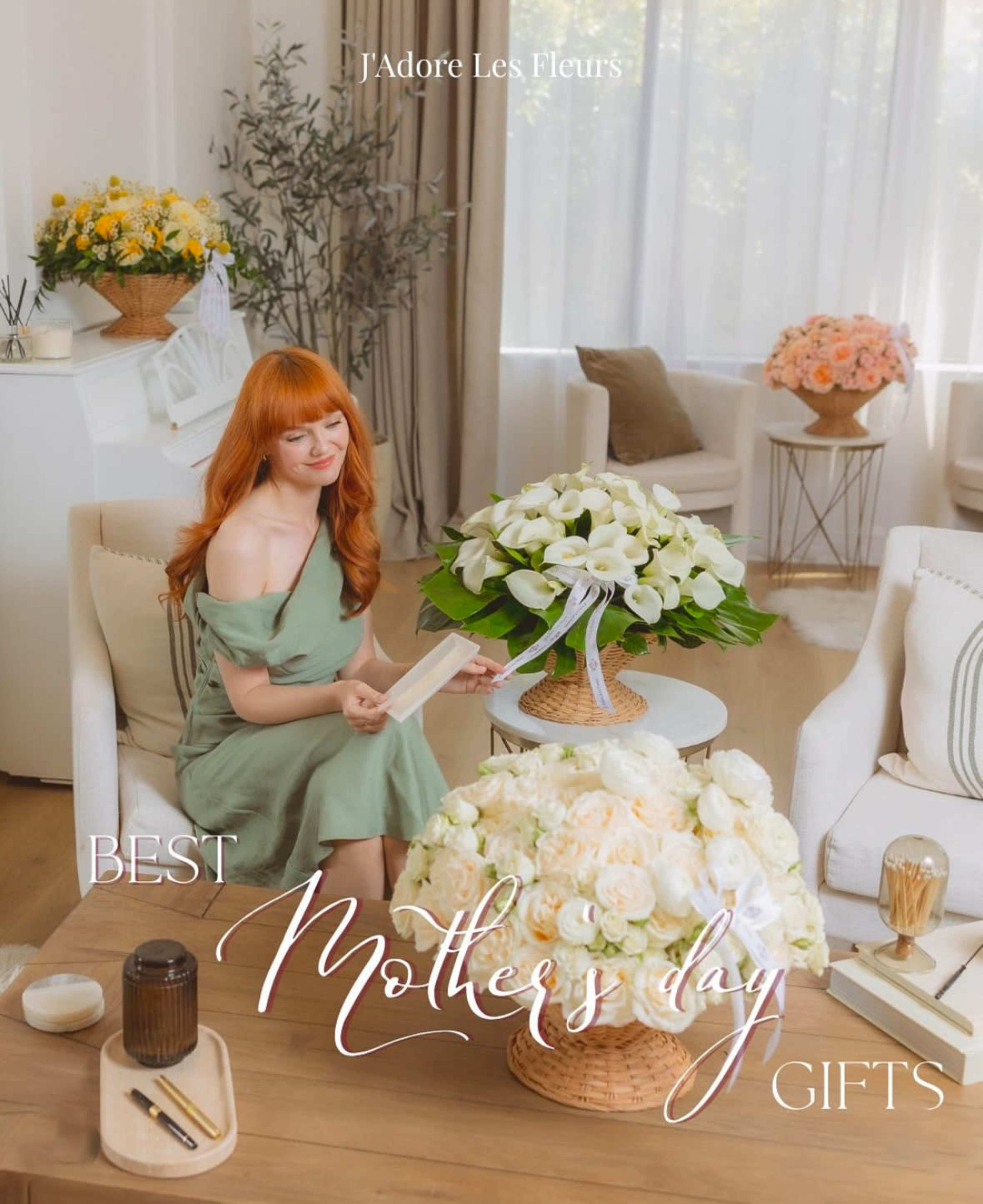 A woman in a green dress sits on a chair in a bright room filled with flower arrangements, holding a book while surrounded by various gift options for Mother's Day.
