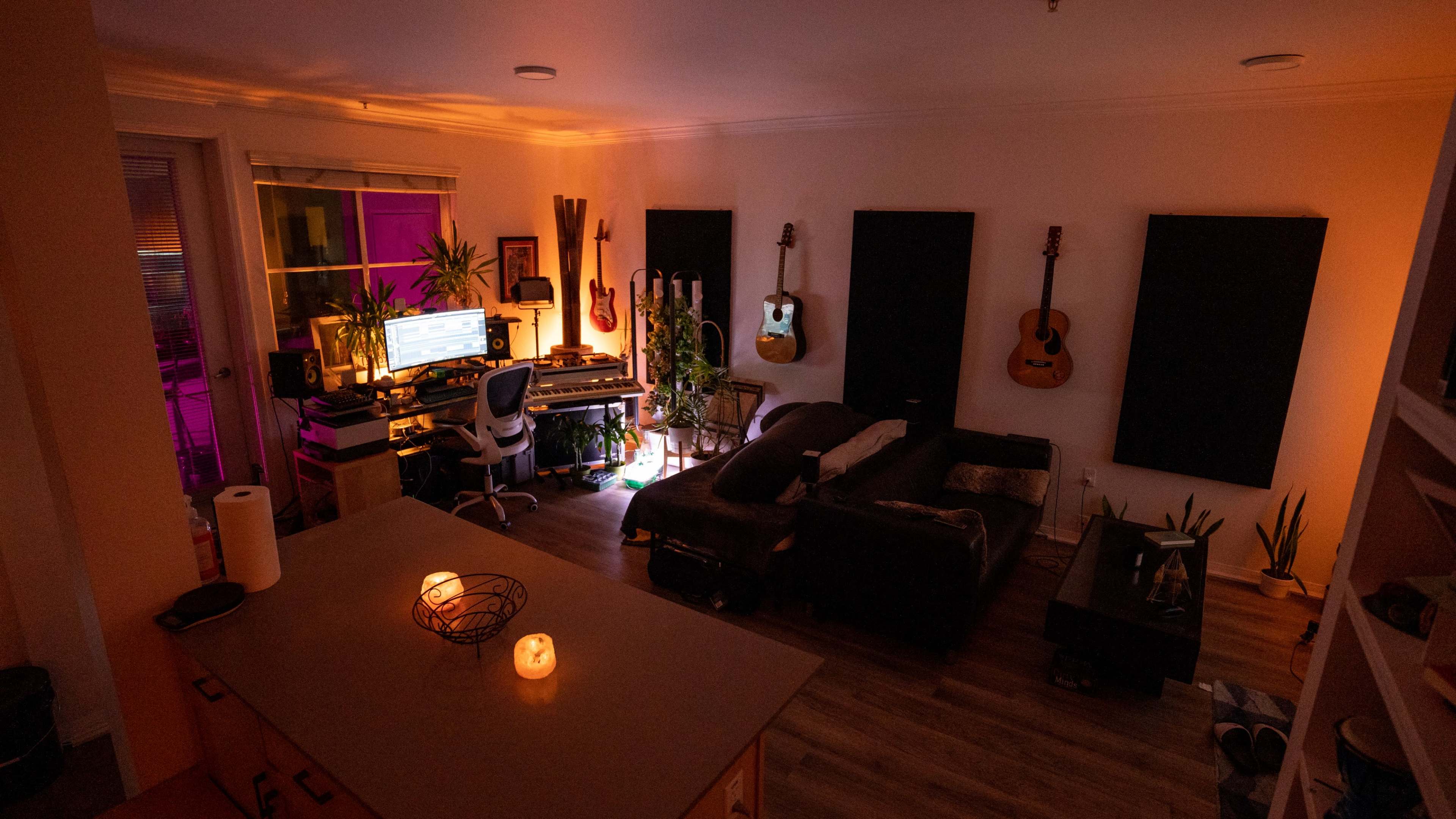 A home studio environment with musical instruments, a computer setup, and ambient lighting.