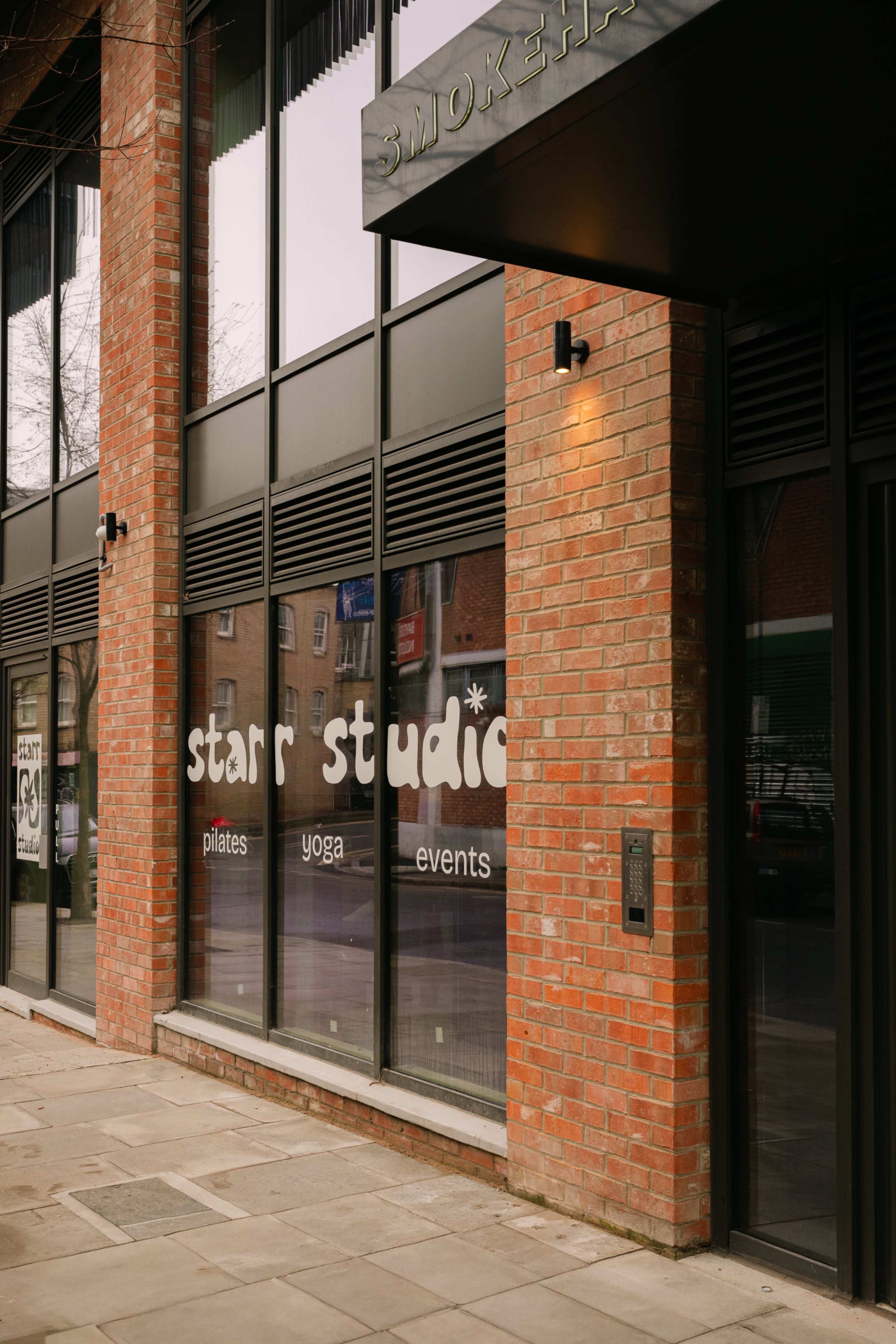 The image shows a brick building with large glass windows displaying the words "star studio" along with the text "pilates," "yoga," and "events."