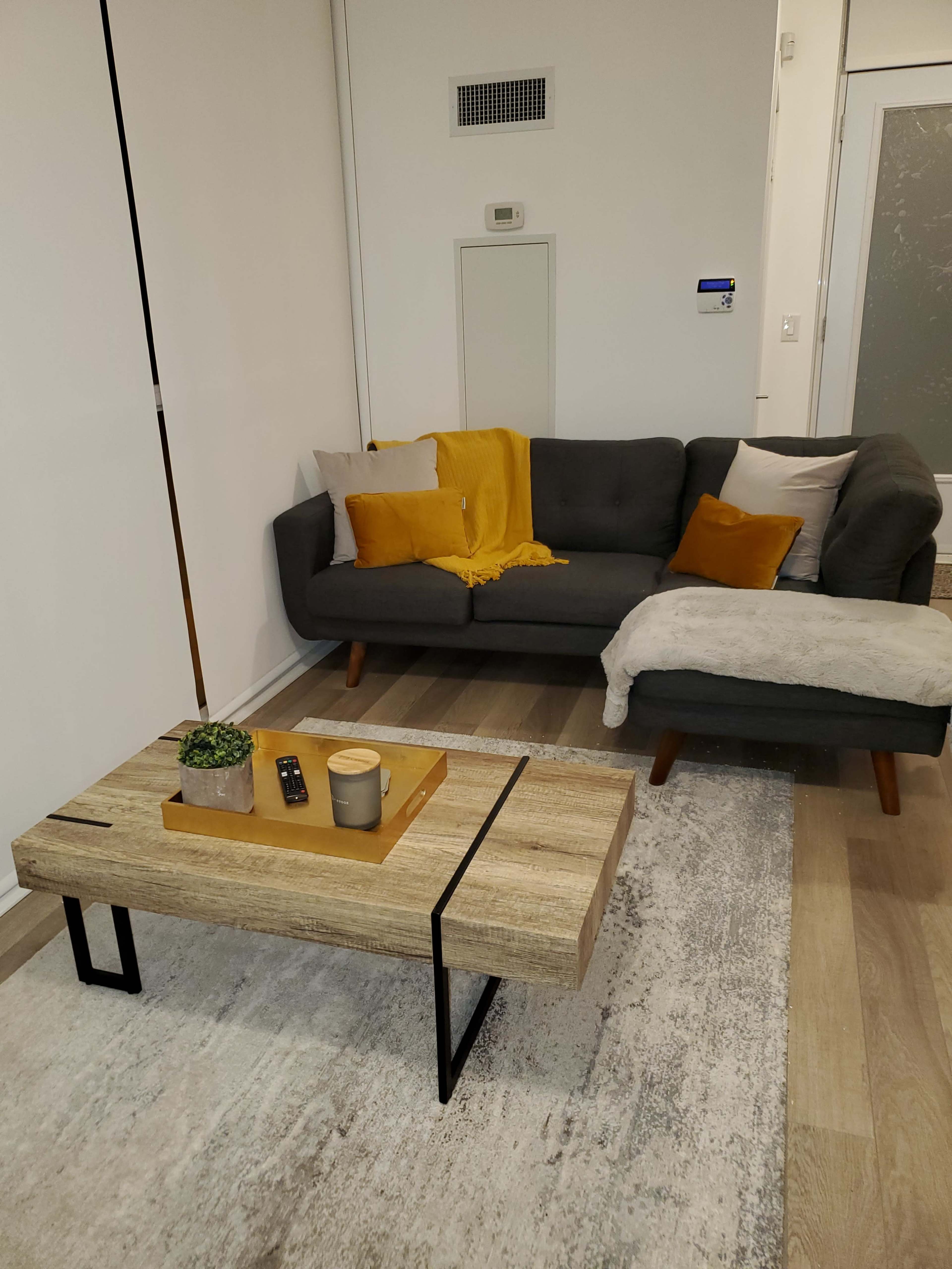 A modern living room with a gray sofa, a wooden coffee table, and a light-colored rug.