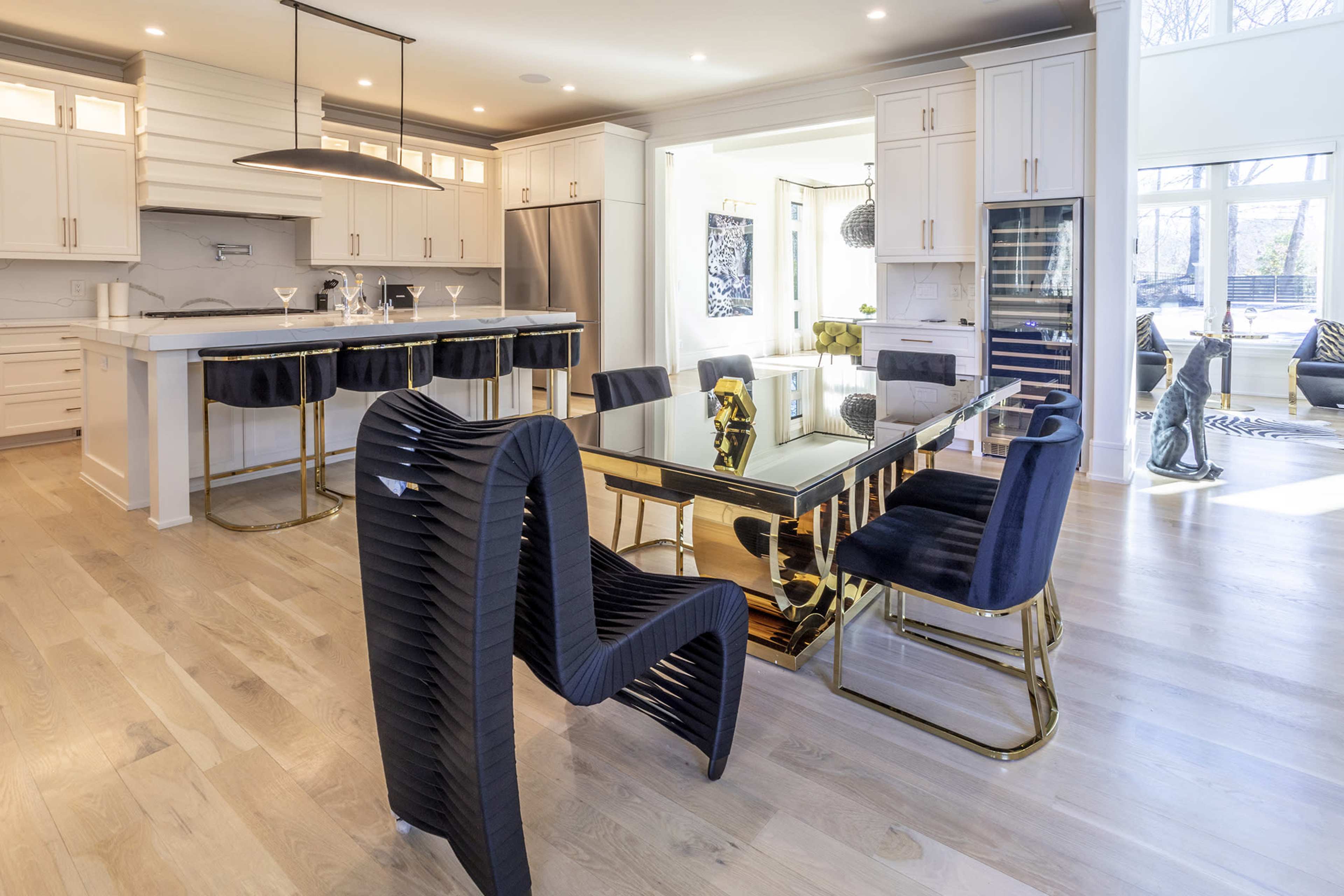 A modern kitchen and dining area with a sleek glass dining table surrounded by black chairs and a spacious island with white cabinetry.