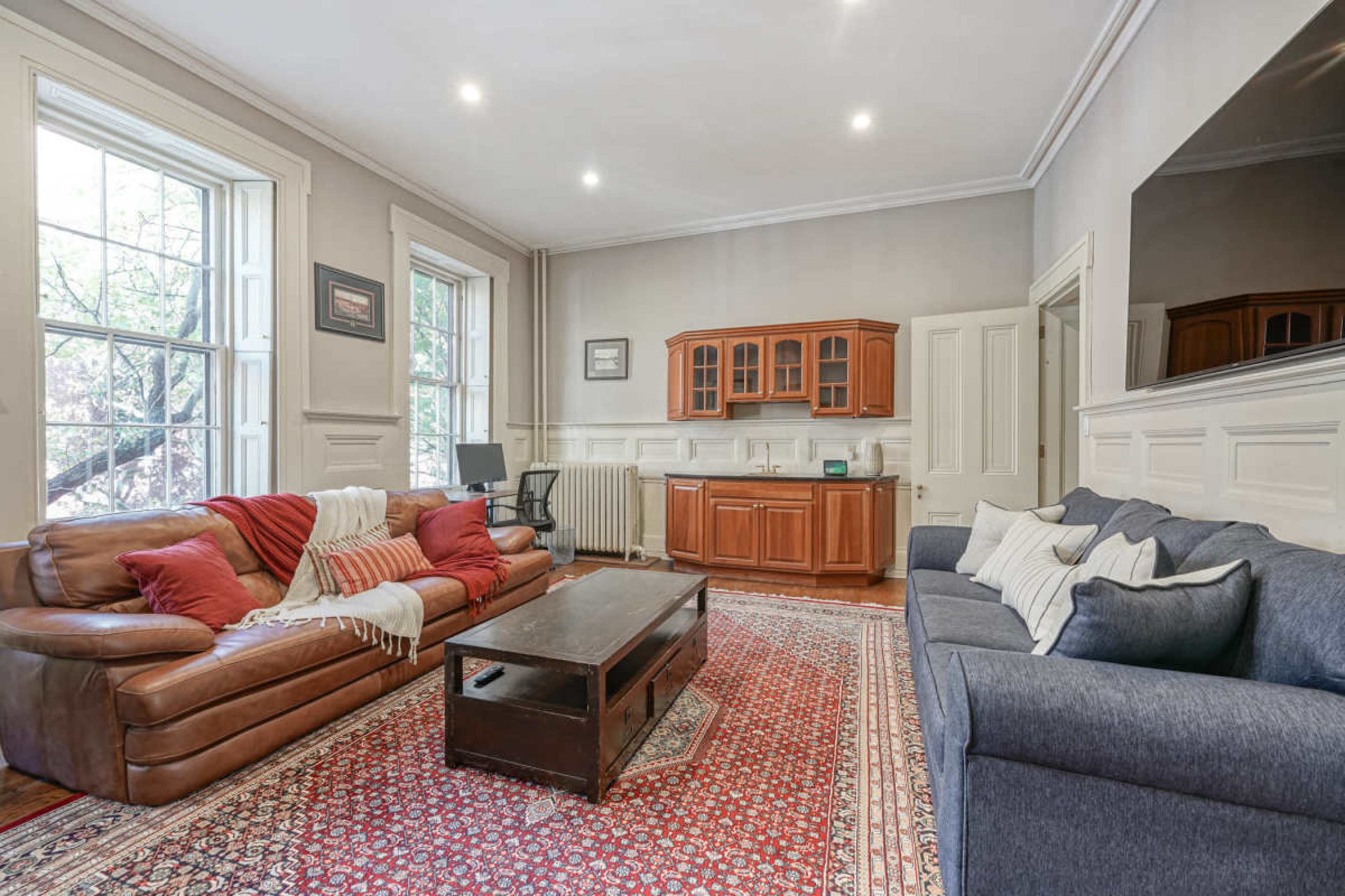 The image shows a spacious living room with two sofas, a coffee table, and a built-in cabinet against the wall.