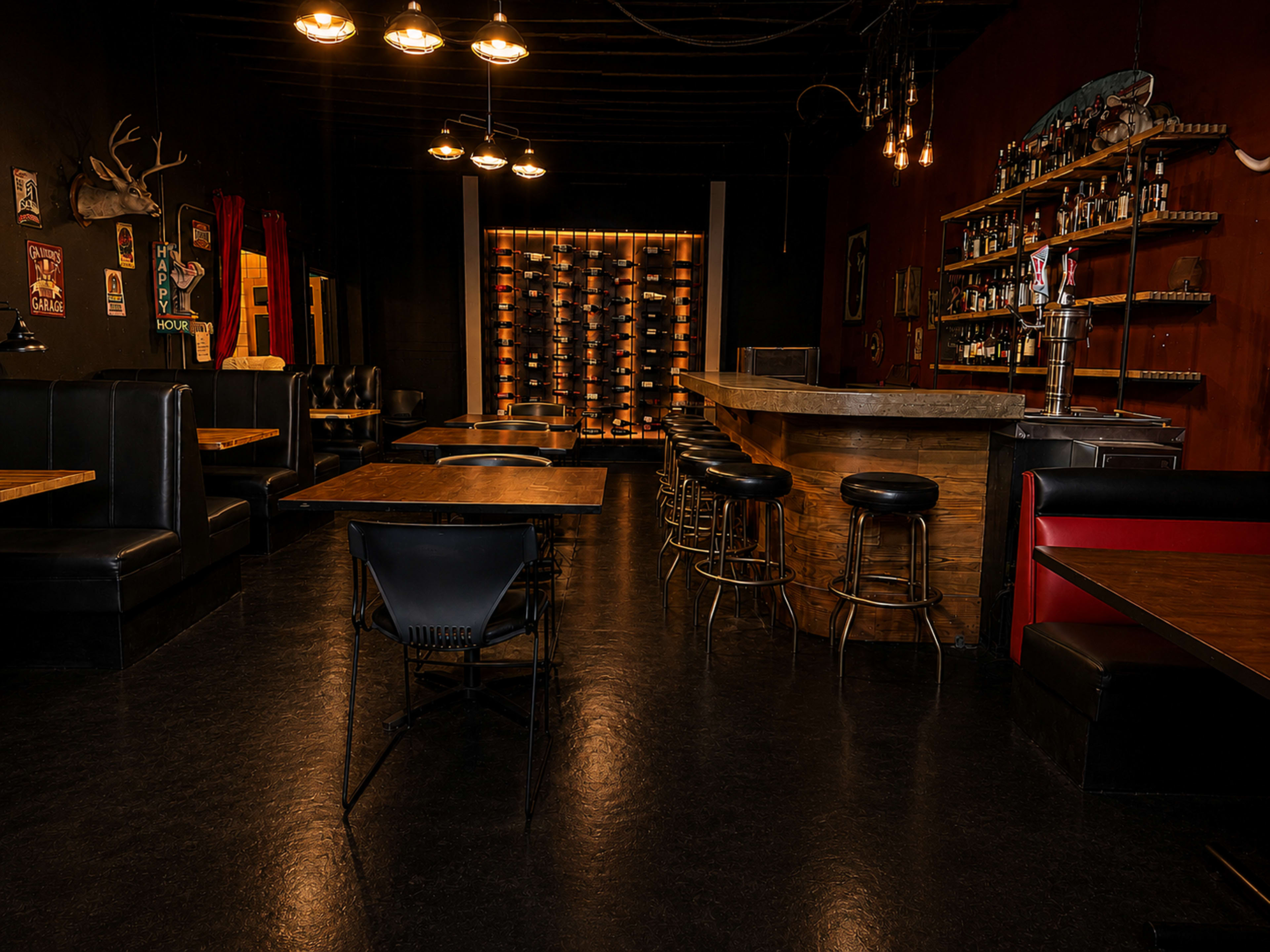 The image shows the interior of a dimly lit bar with black booths, a wooden bar counter, and a wine rack in the background.