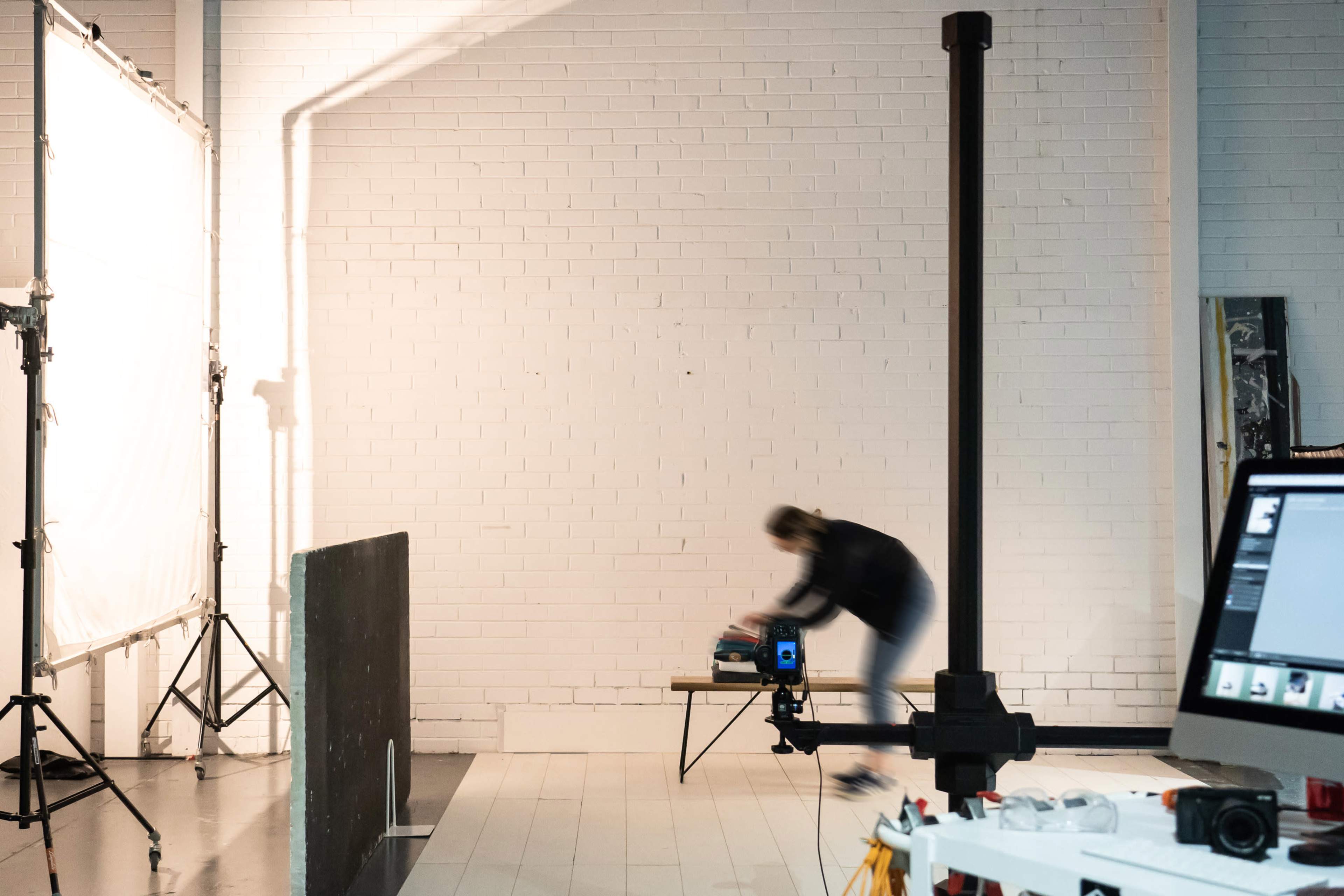 A person in motion places items on a table in a well-lit studio space.