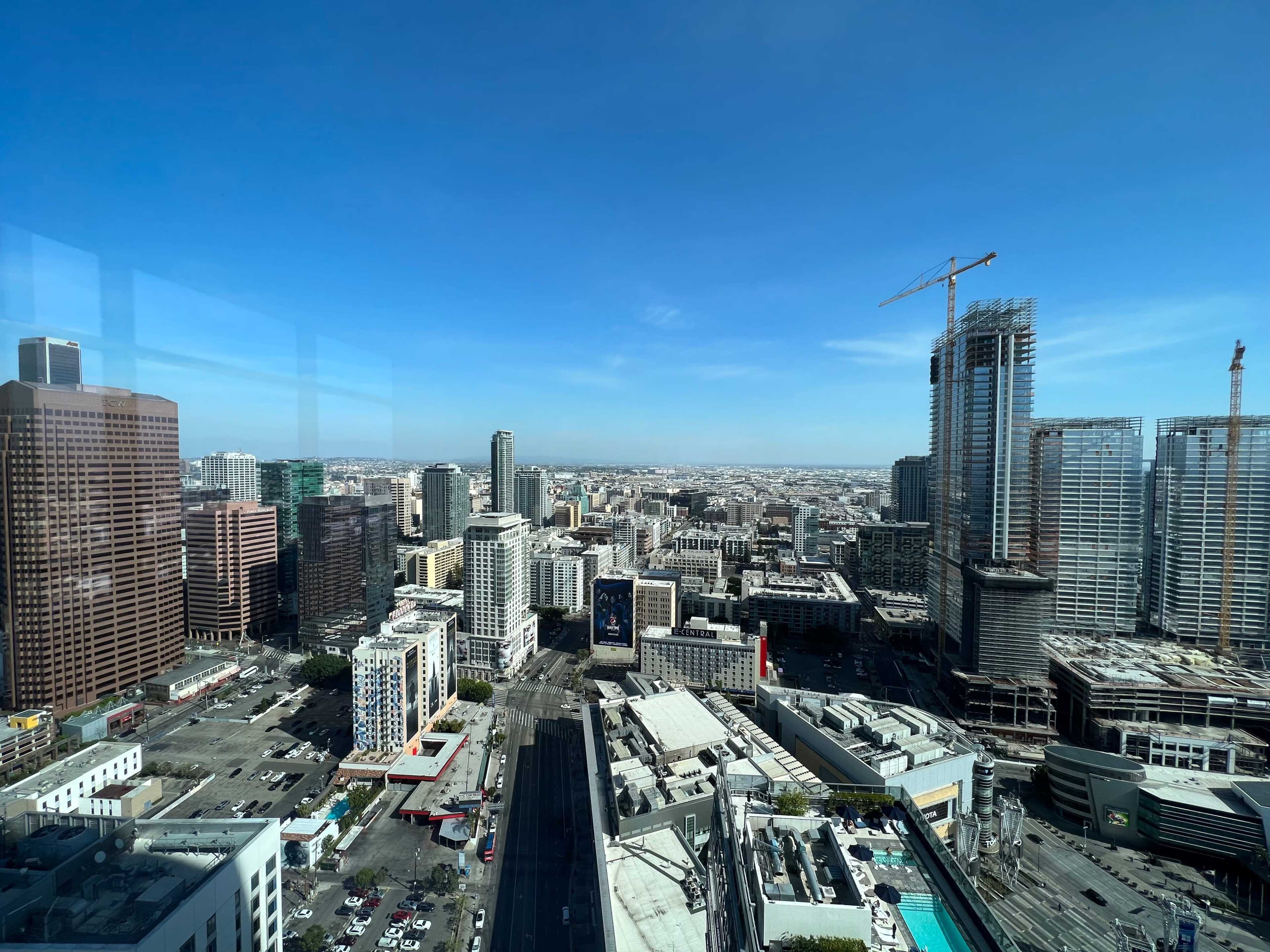 A city skyline features tall buildings, a construction site, and visible streets with parked cars.