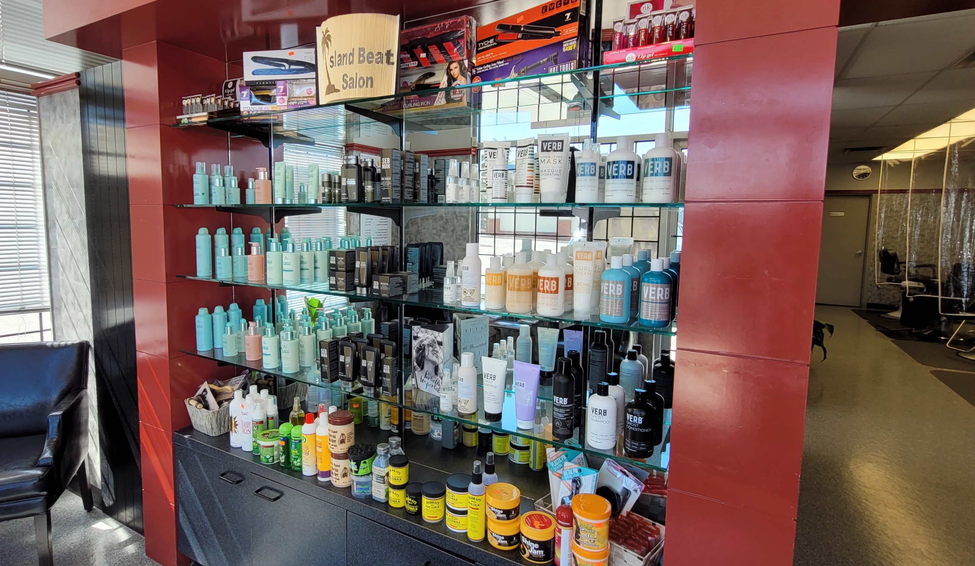 A display shelf filled with various hair and beauty products arranged on glass shelves in a salon.