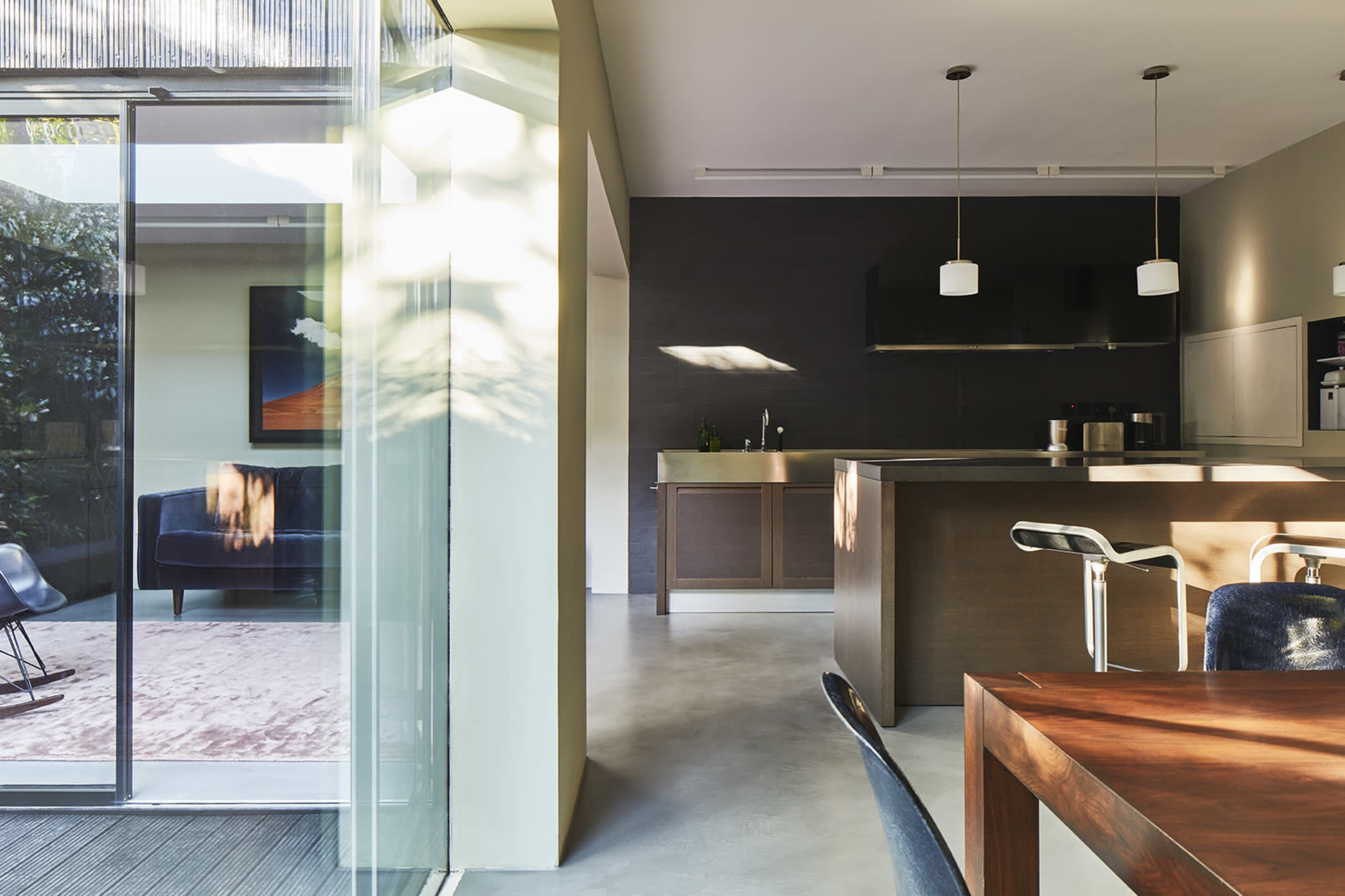 A modern kitchen and dining area with an open layout, featuring a kitchen island, dining table, and large glass doors leading to an outdoor space.