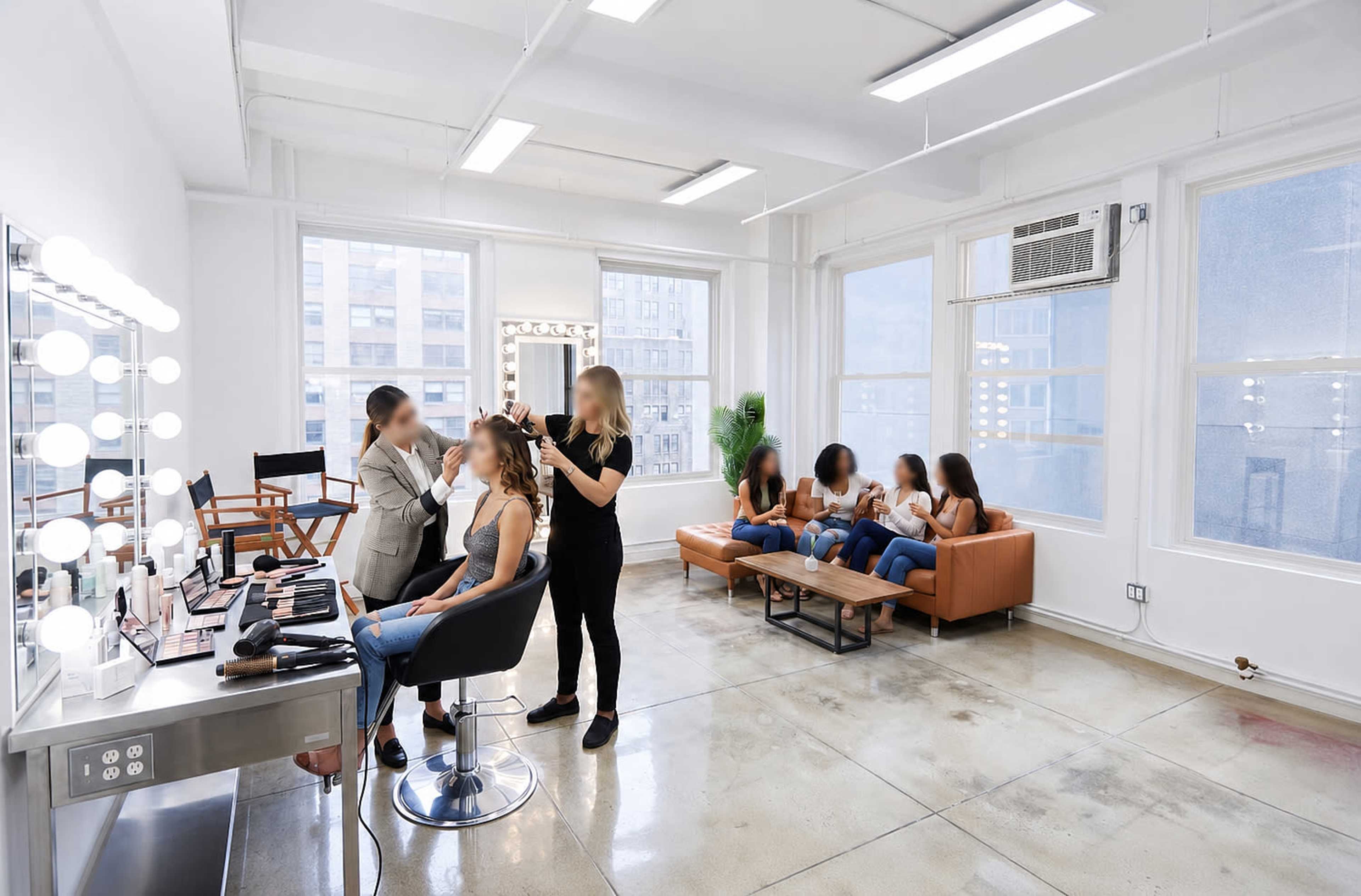 A bright salon features two stylists working on clients, while others are seated on couches, waiting.