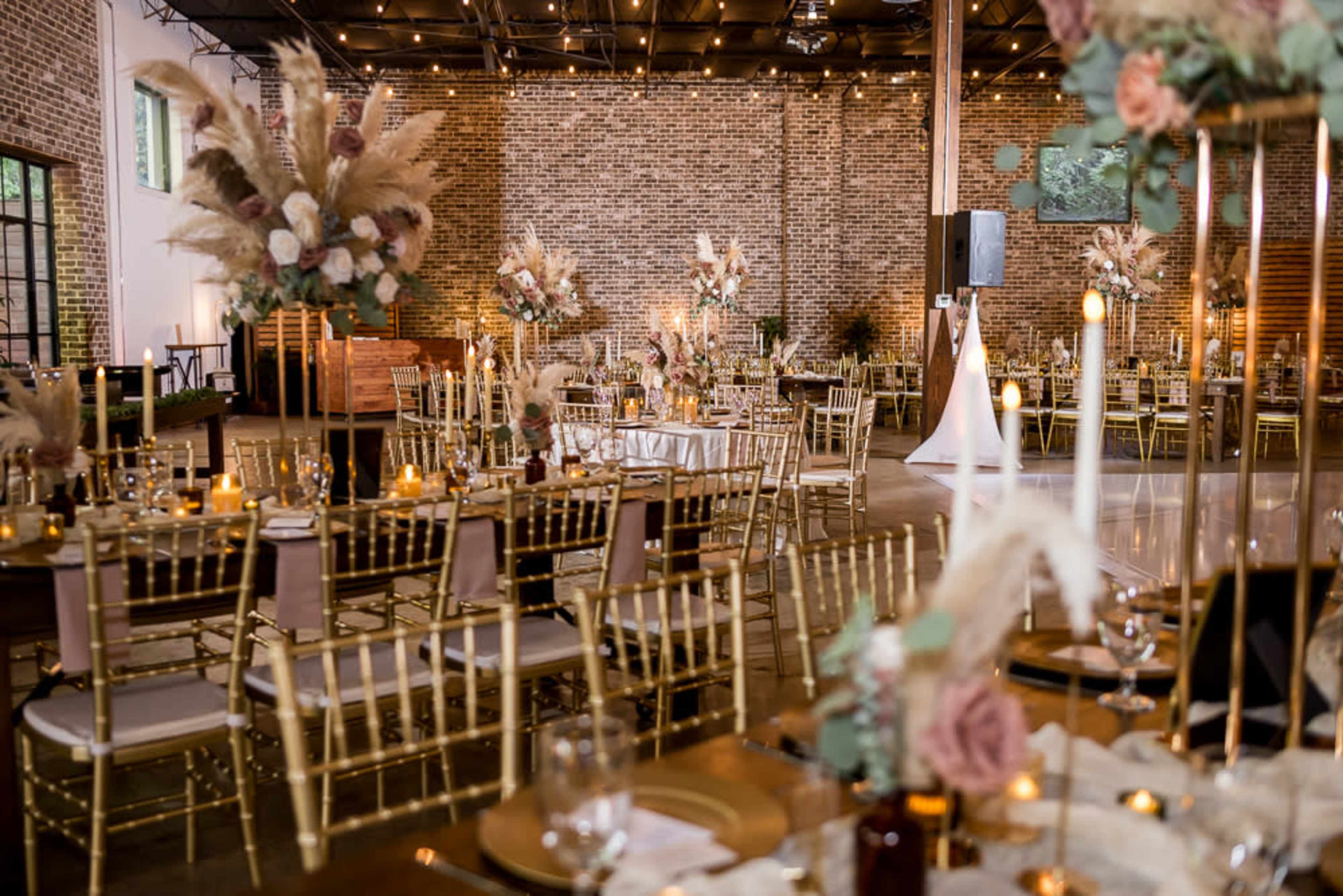 The scene shows a beautifully decorated event space with long tables, elegant chairs, and elaborate floral arrangements under soft lighting.