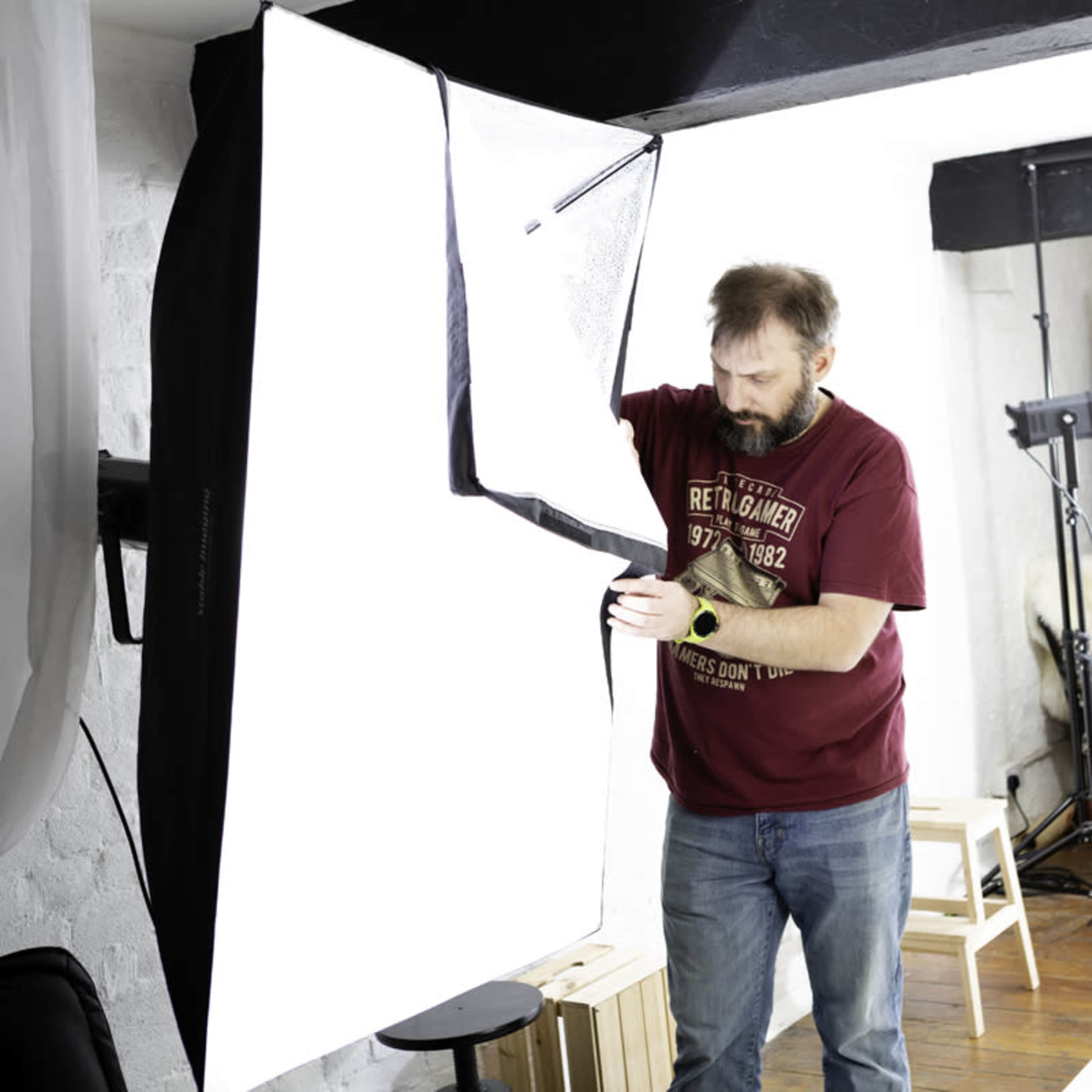 A man is adjusting a large white softbox light in a studio setting.