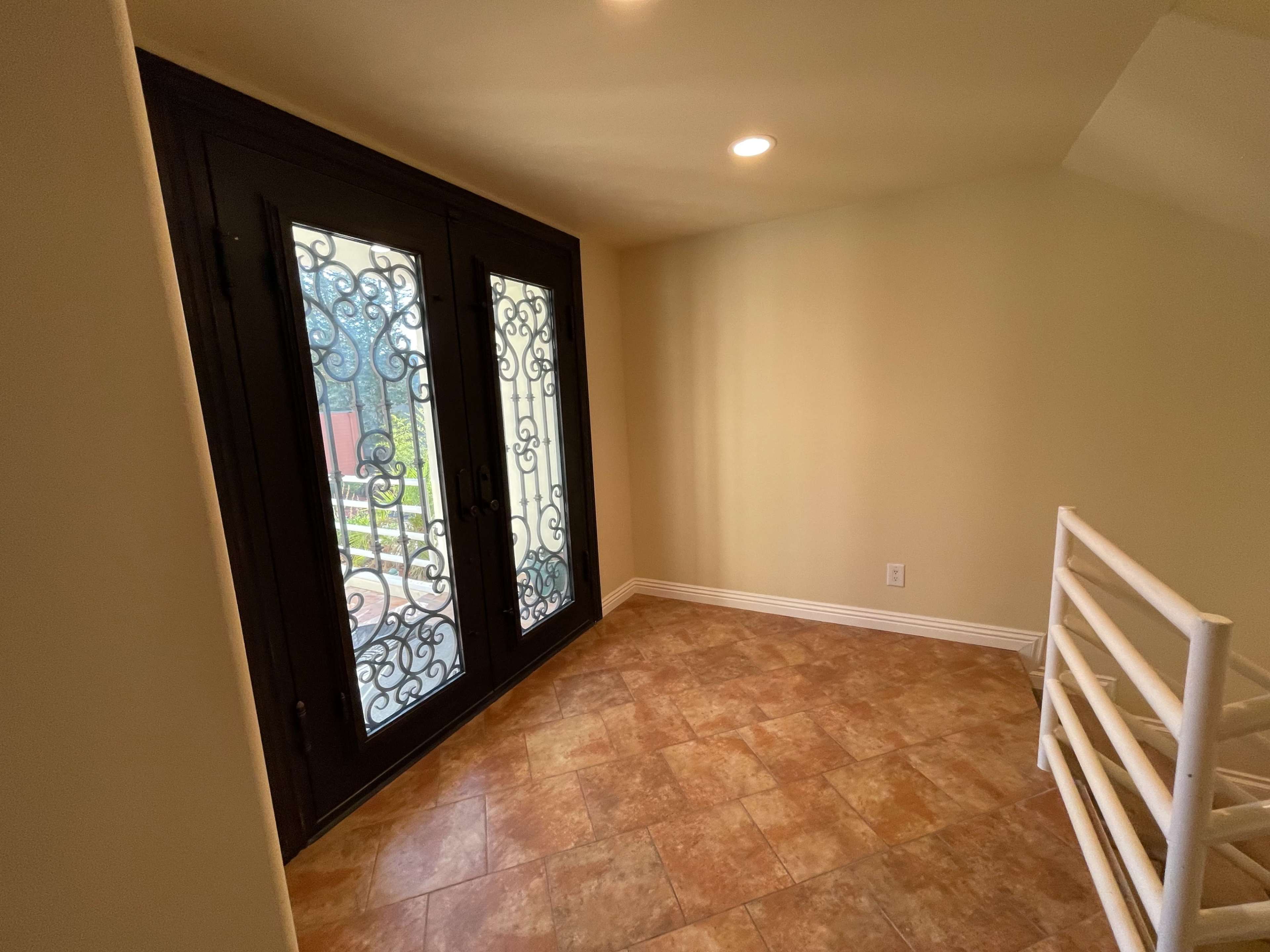 A well-lit corner of a room featuring large decorative iron-framed doors and tiled flooring.