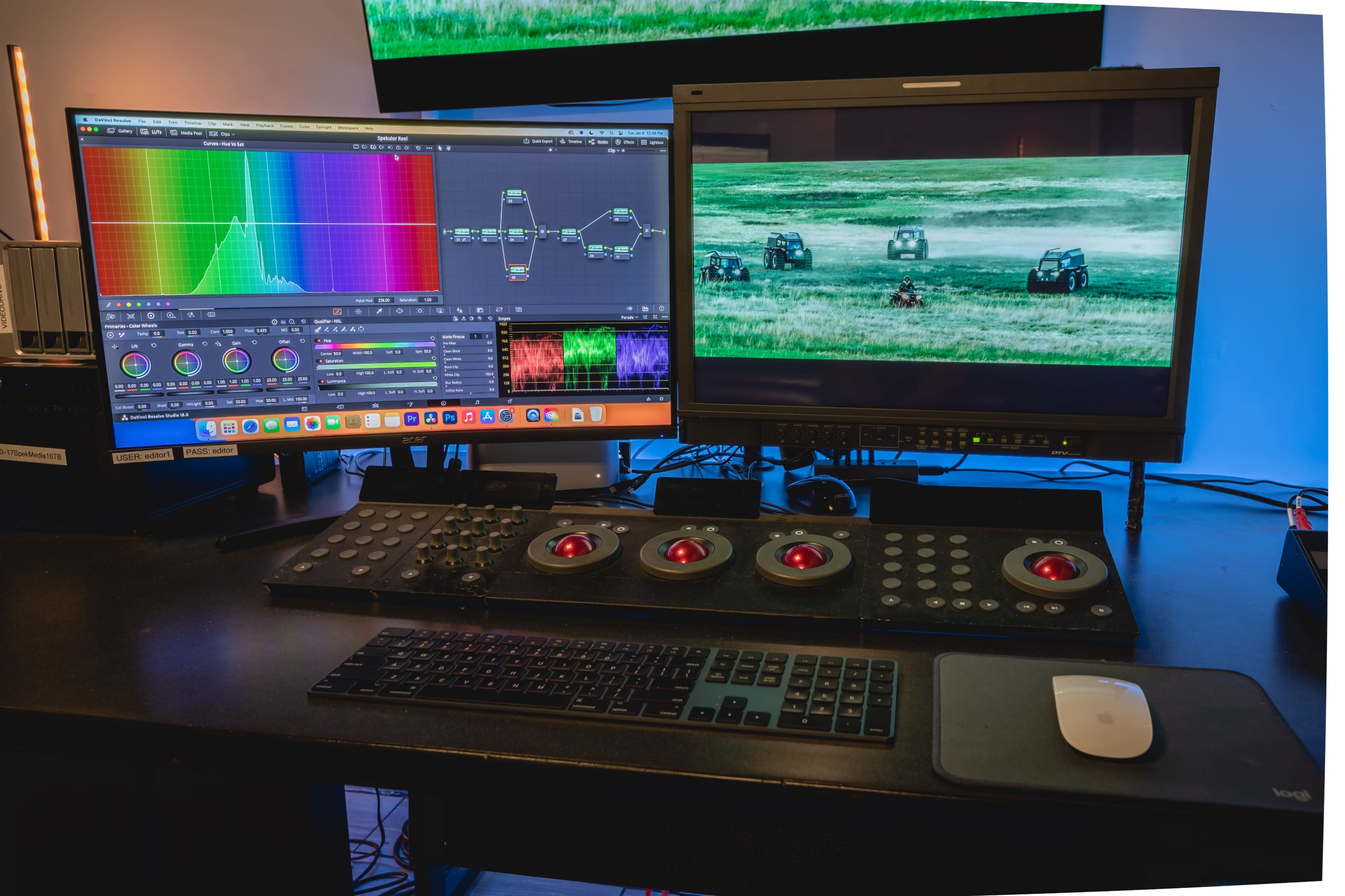 A color grading workstation with two large monitors displaying editing software and a video clip, along with a control panel featuring multiple dials and buttons.