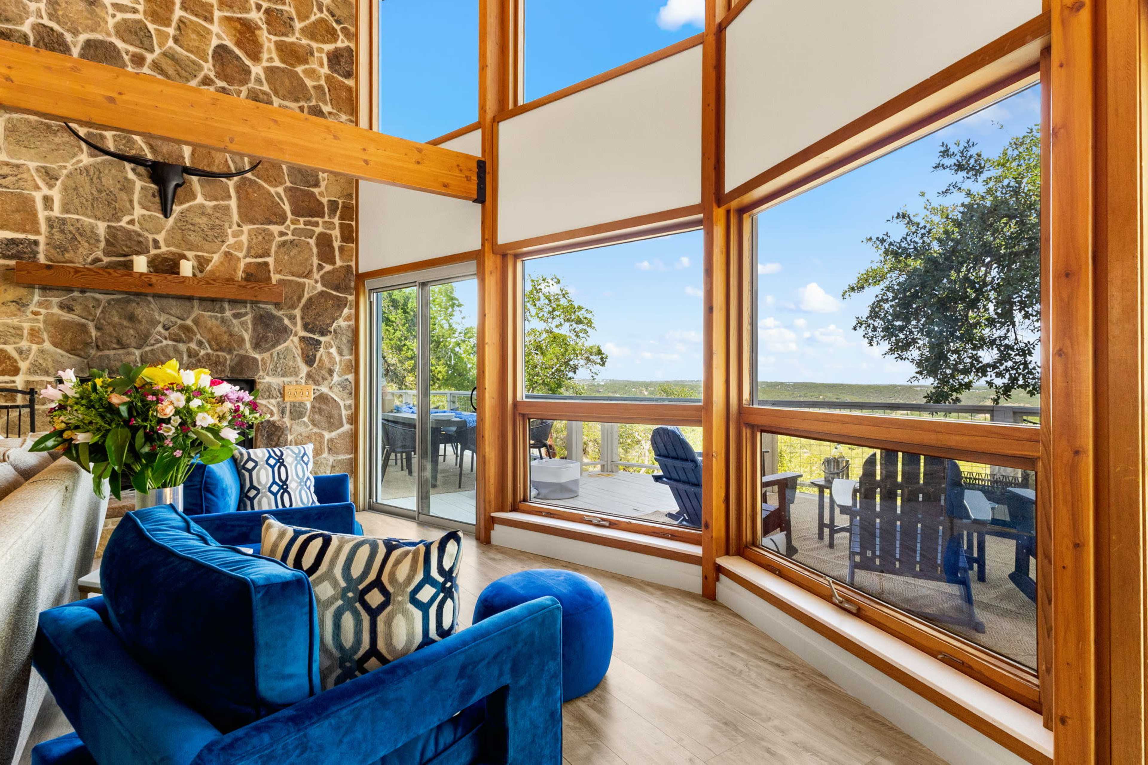 A cozy living area features blue chairs and a stone wall, with large windows that provide a view of the outdoors.
