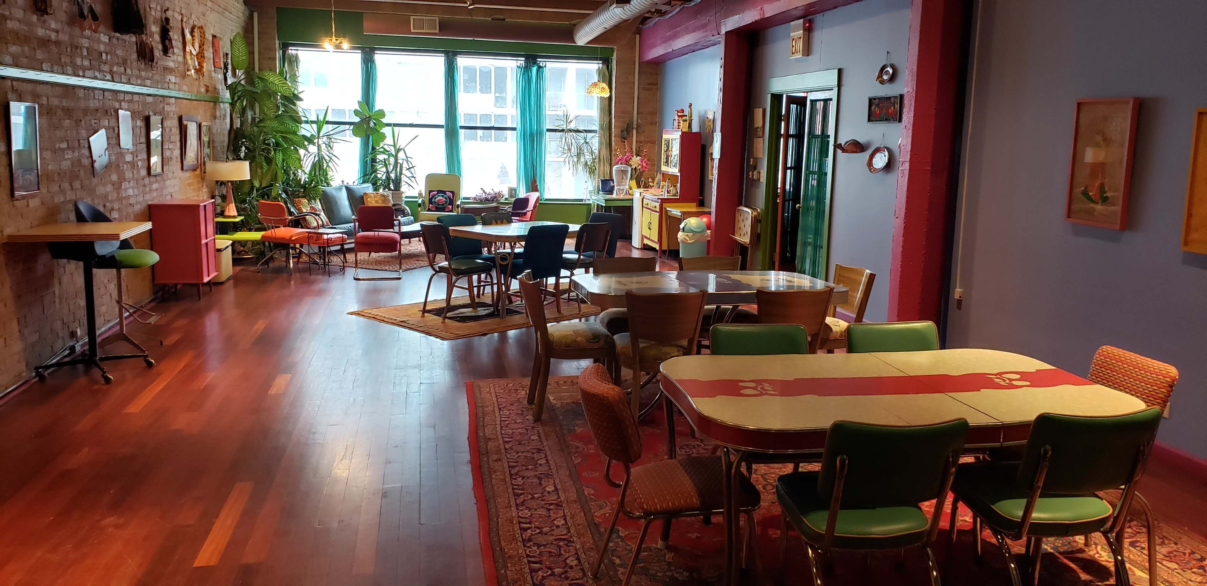 A vibrant, open interior space with various seating arrangements, plants, and decorative art on the walls.
